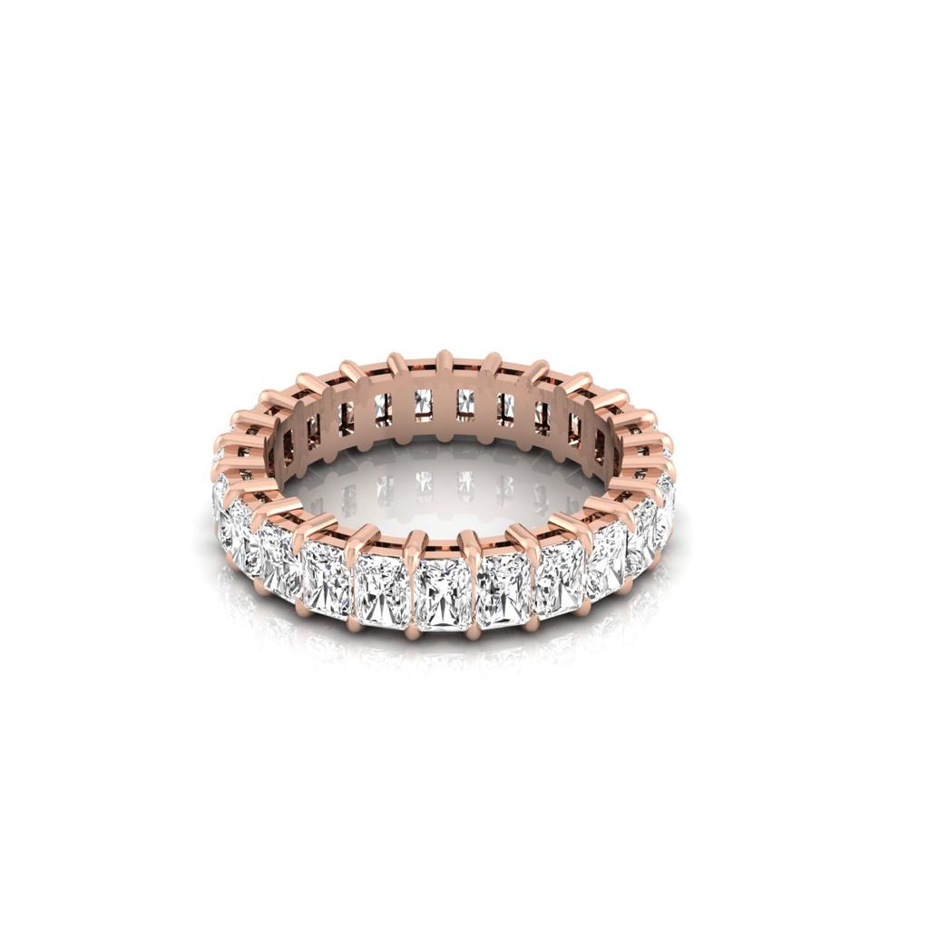The Full Lab Grown Diamond Eternity Ring features an 18KT rose gold band with prong-set, round-cut F Color VS Clarity diamonds in a continuous circle, elegantly showcased on a reflective white surface.