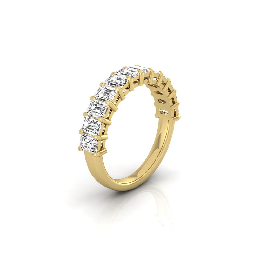 The Half Diamond Eternity Ring is an 18KT gold band featuring rectangular clear gemstones with VS Clarity, elegantly set along the top half, displayed against a pristine white background.