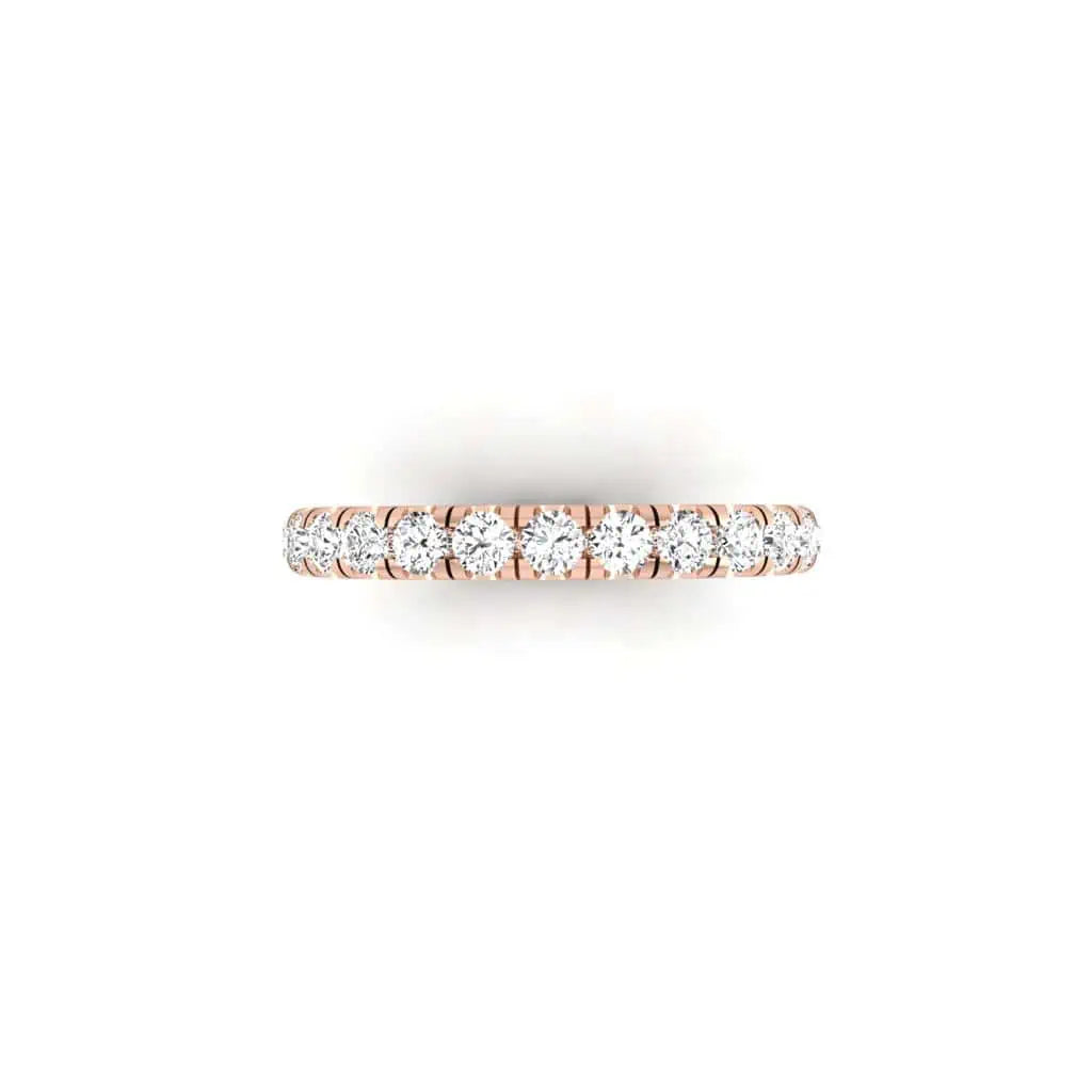 The 1ct Round Diamond Eternity Ring features an 18KT rose gold band adorned with a row of small, sparkling white diamonds in VS clarity, set closely together against a simple white backdrop.