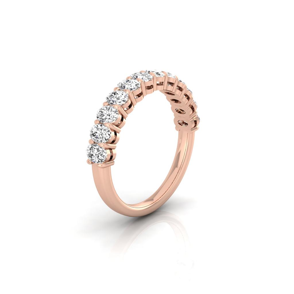 The Half Diamond Eternity Ring in 18KT rose gold features a curved band with round, VS clarity diamonds. Elegantly angled on a reflective white surface, it exudes timeless sophistication.