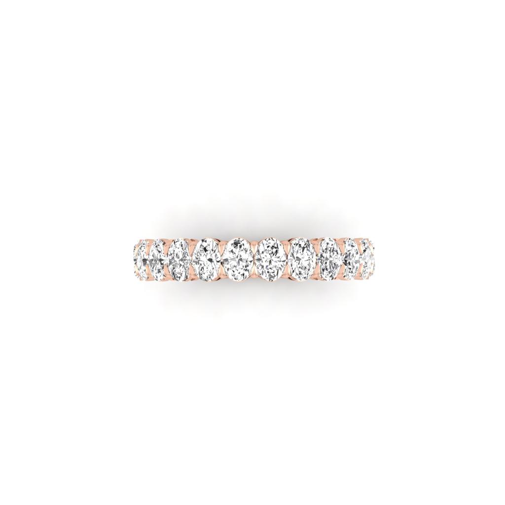 The Half Diamond Eternity Ring is crafted in 18KT rose gold, featuring a continuous row of round-cut diamonds with VS clarity across the top. Displayed elegantly on a plain white background, its design is both minimalist and refined.