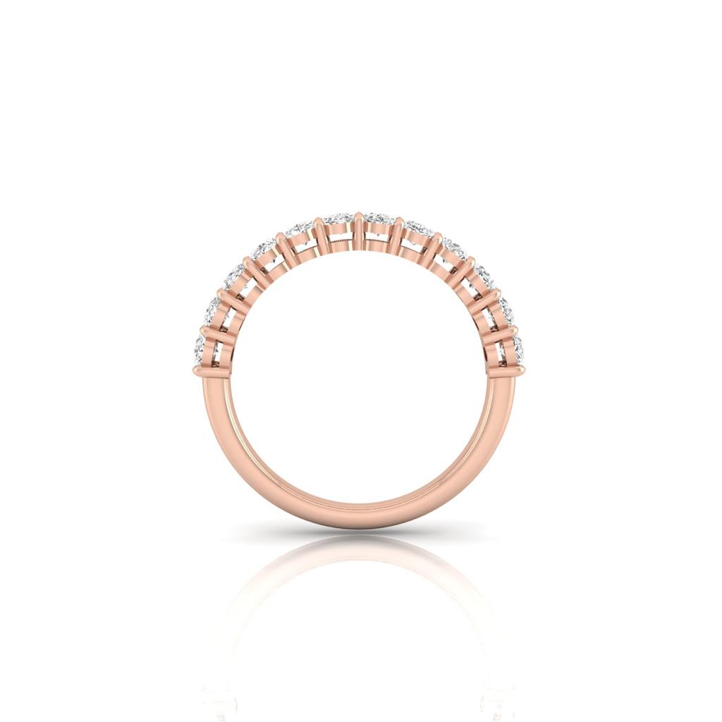 The Half Diamond Eternity Ring features a half circle of stunning, sparkling diamonds in VS clarity set in 18KT rose gold. It is displayed vertically on a white background, creating a subtle reflection below.