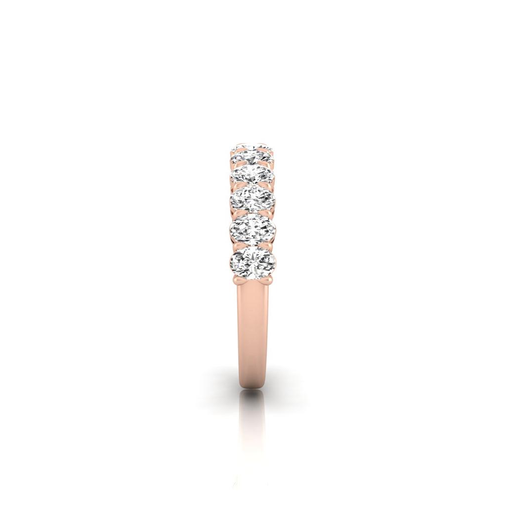 The Half Diamond Eternity Ring is crafted from 18KT rose gold featuring five round-cut VS clarity diamonds set in a row, reflecting light to enhance elegance against a plain white background.