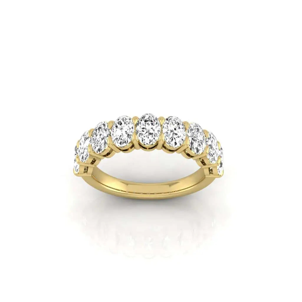 The Half Diamond Eternity Ring, crafted in 18KT gold, features a row of sparkling round diamonds with VS Clarity. Its elegantly positioned upright against a white background to highlight its shimmering beauty.