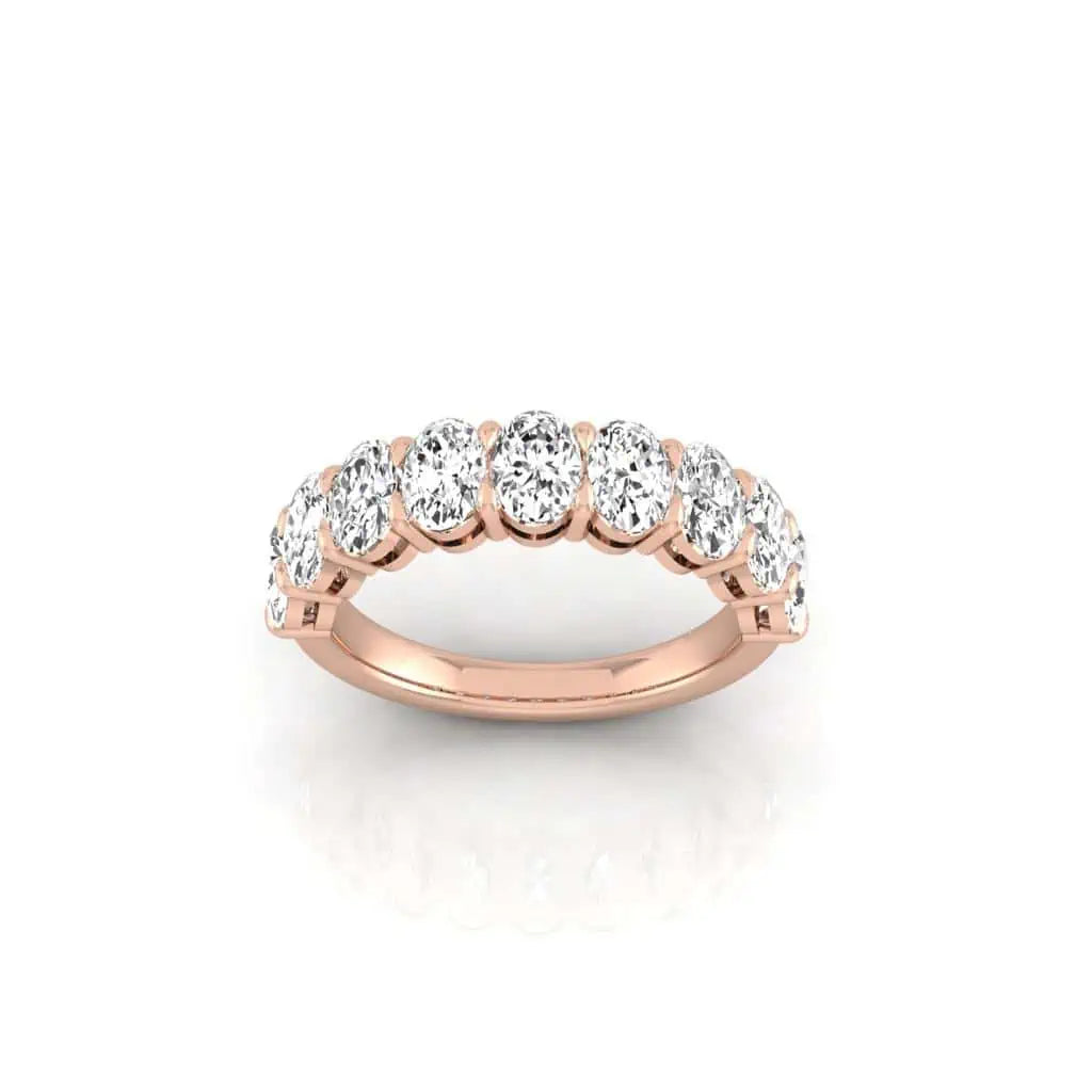 The Half Diamond Eternity Ring, crafted in 18KT rose gold, features a row of sparkling round diamonds with VS clarity set across the top and is displayed against a plain white background.