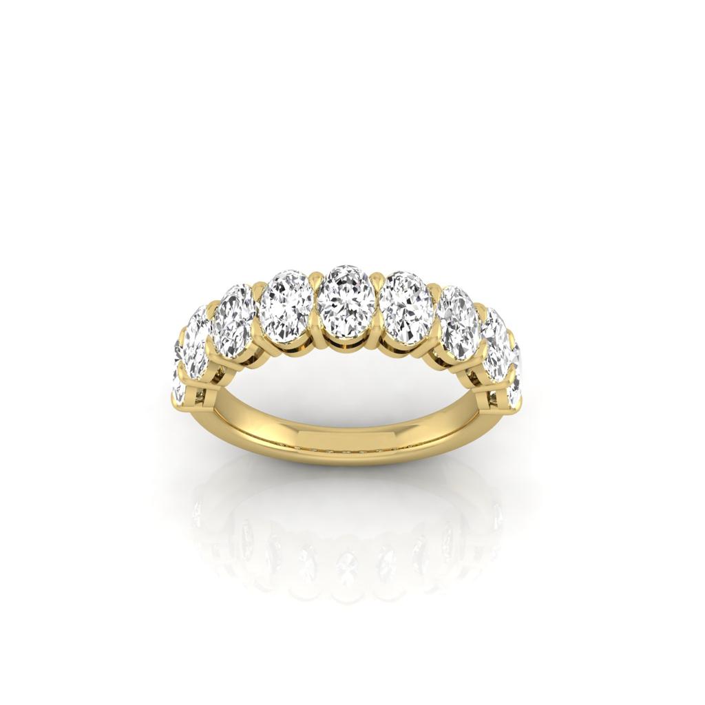 The Half Diamond Eternity Ring is an 18KT gold band adorned with a row of round, sparkling VS Clarity diamonds, beautifully displayed on a reflective white surface.