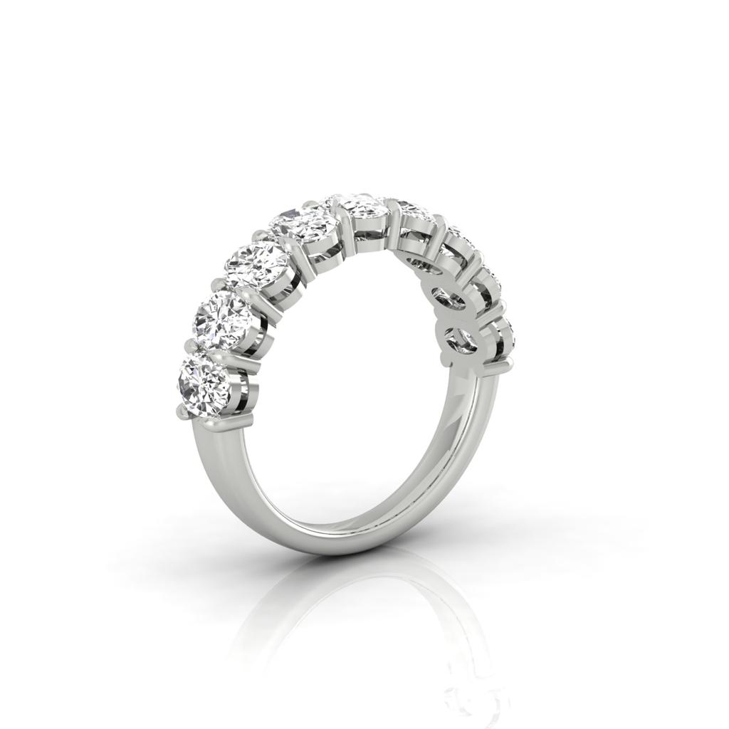 The Half Diamond Eternity Ring is a silver band with nine sparkling diamonds of VS Clarity set in a row, showcased on a reflective surface to highlight its elegance and 18KT Gold craftsmanship.