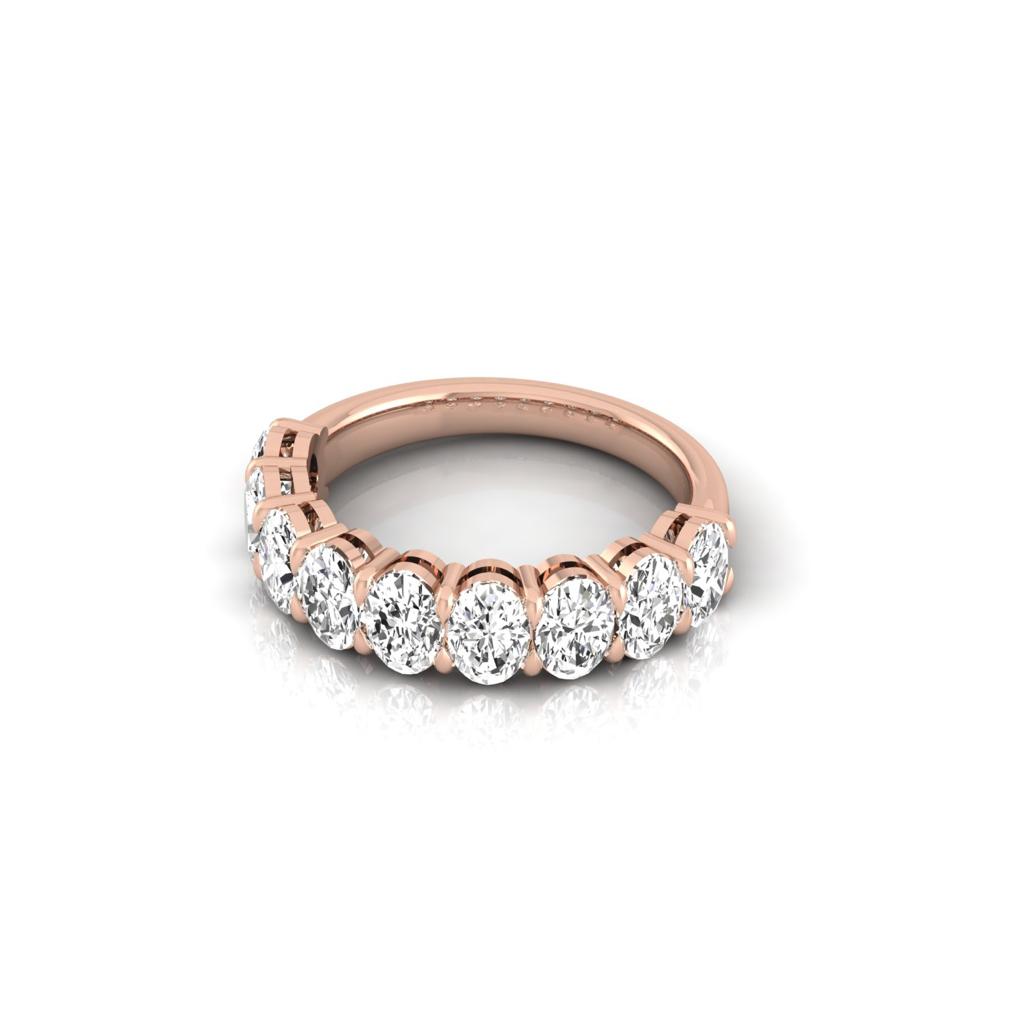 The Half Diamond Eternity Ring, crafted from 18KT rose gold, features a linear array of eight round white diamonds with VS Clarity. Set against a simple white backdrop, its elegant design and sparkling brilliance are beautifully highlighted.