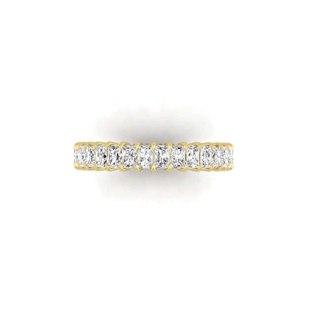 The Full Diamond Eternity Ring is an 18KT gold band adorned with F Color, VS Clarity diamonds set in a row, all showcased on a plain white background. Its symmetrical design highlights the brilliance of each diamond.