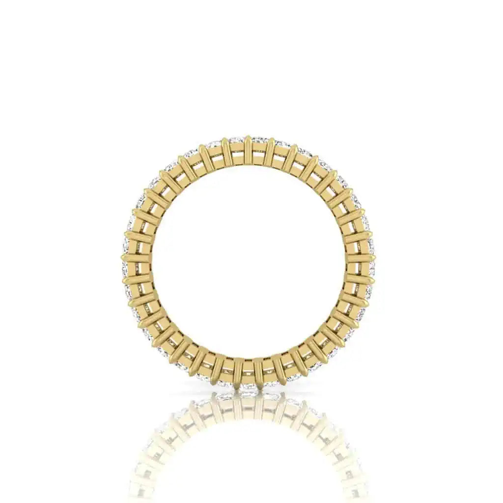 The Full Diamond Eternity Ring, crafted in 18KT gold with an intricate pattern and VS Clarity diamonds evenly spaced, is elegantly presented on a reflective white surface.