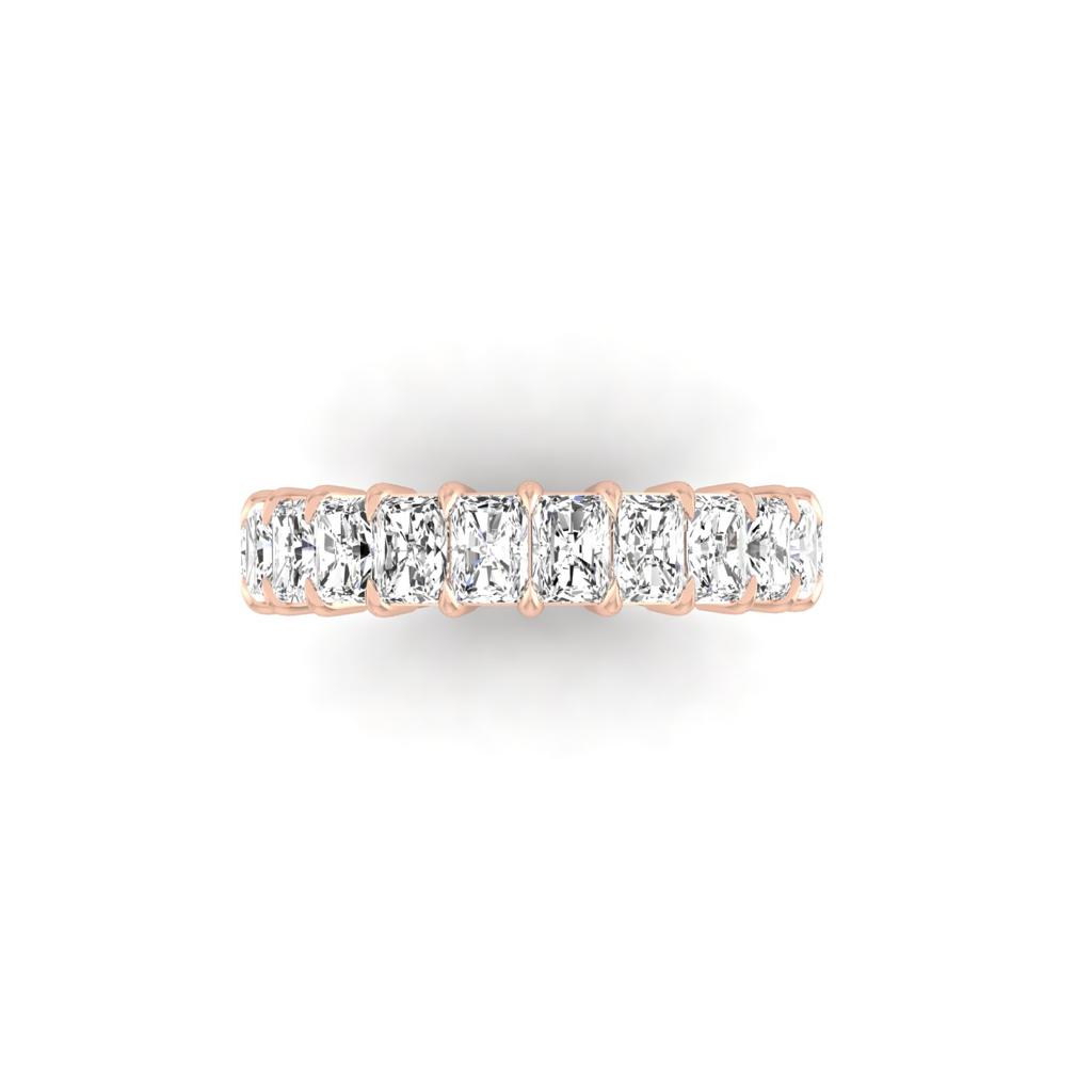 The Full Lab Grown Diamond Eternity Ring, crafted in 18KT rose gold, showcases large rectangular-cut gemstones arranged continuously, with F Color VS Clarity stones. Against a plain white background, it exudes a sparkling and elegant design.