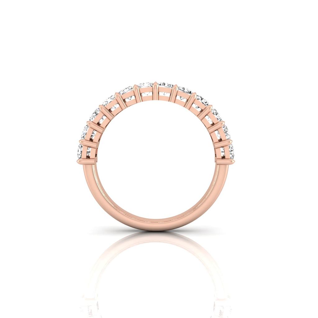The Half Diamond Eternity Ring in 18KT rose gold is set vertically, featuring VS Clarity diamonds along its top half. The side view highlights the symmetrical design and dazzling shine of the gemstones against a pristine white background.