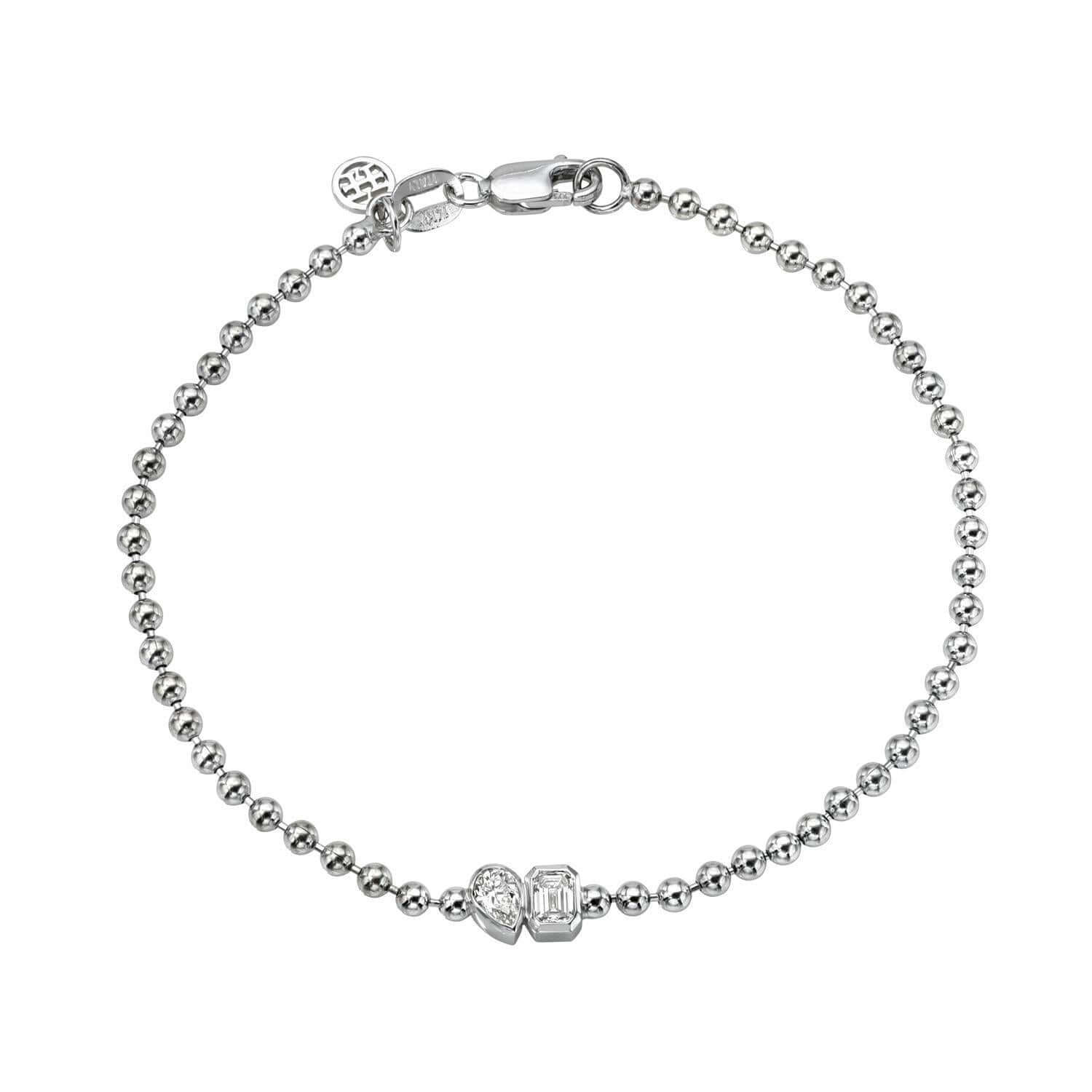 The Emerald & Pear Toi Et Moi Bracelet is a silver bead bracelet with a lobster clasp, featuring a small round charm symbolizing love and an ornamental piece near the clasp, celebrating partnerships.