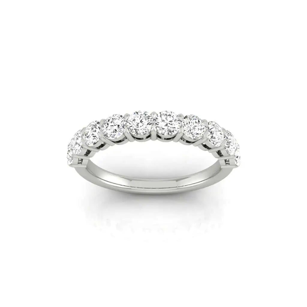 The Half Diamond Eternity Ring is a silver band adorned with seven round diamonds in VS Clarity, symmetrically set to glitter beautifully. The plain white backdrop highlights its elegant design.