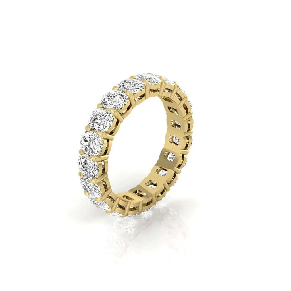 The Full Diamond Eternity Ring, made from 18KT gold and set with round F Color VS Clarity diamonds, glistens in a seamless circle. It stands upright on a reflective surface, highlighting its exquisite design against a simple white background.