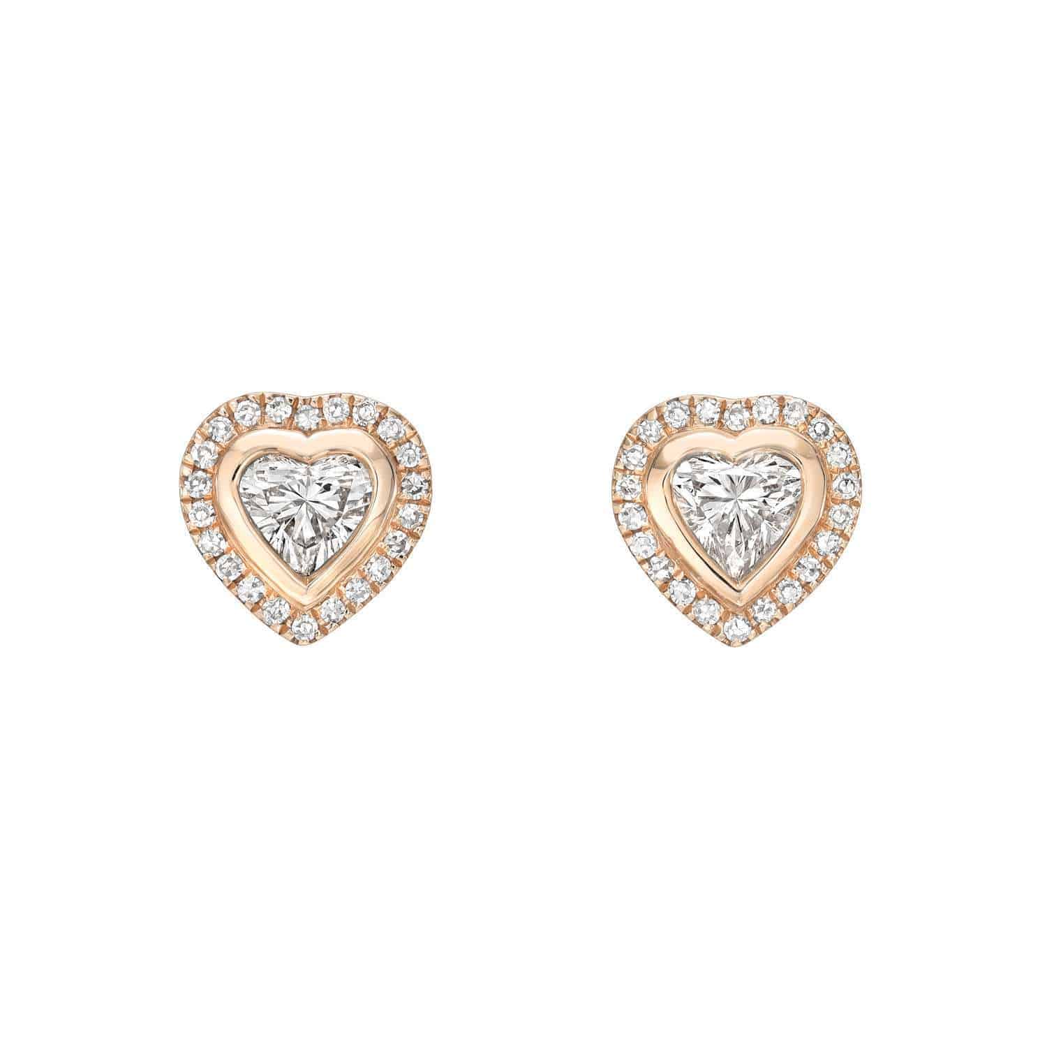 The Heart-Shaped Diamond Halo Studs by Janet Heller Fine Jewelry feature heart-shaped diamonds set in gold, each encircled by a sparkling halo of round diamonds, and are displayed on a white background to showcase their timeless elegance.