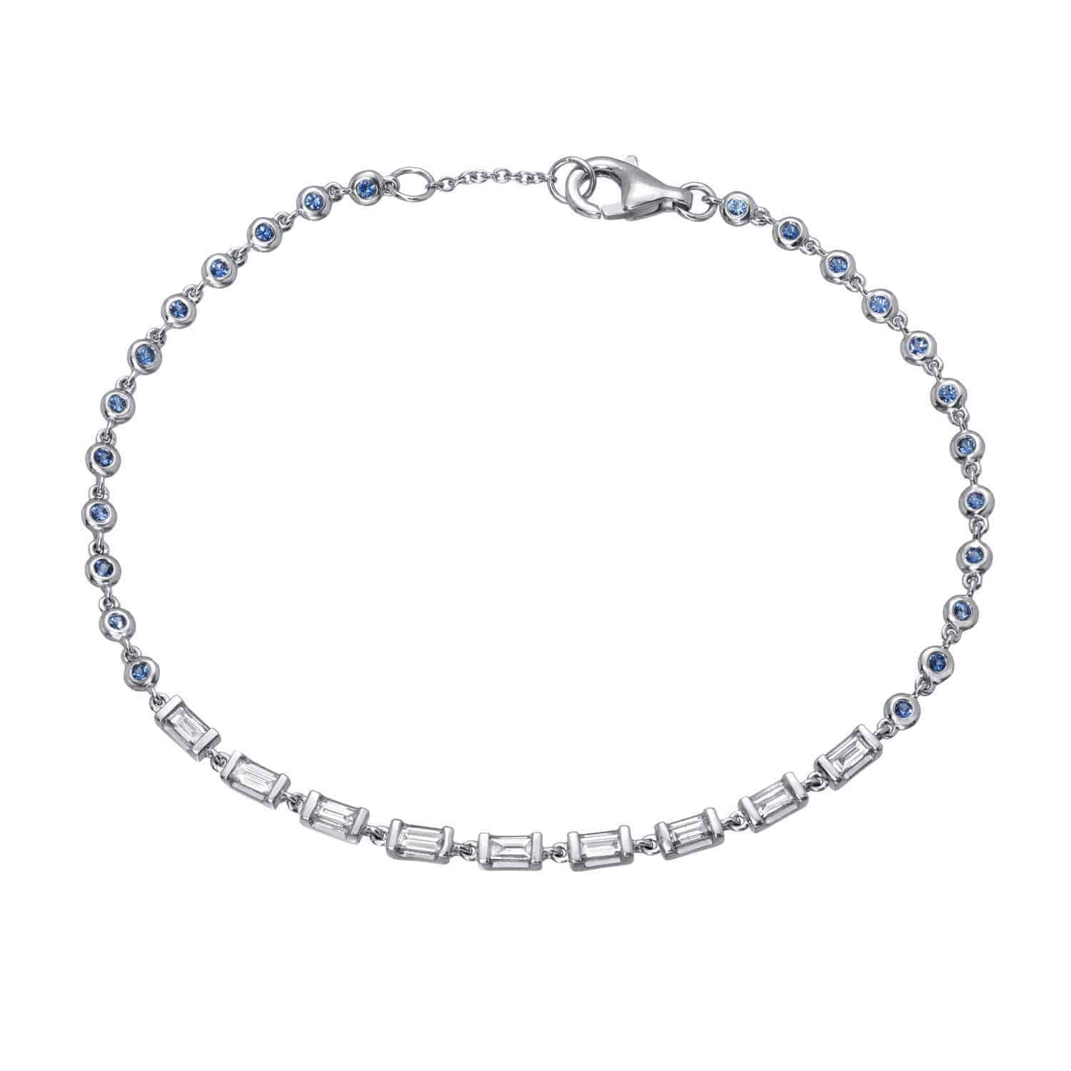 Introducing the Baguette and Sapphire Bracelet: a silver bracelet featuring alternating round blue sapphires and rectangular clear gemstones, secured with a lobster claw clasp. This elegant piece showcases Janet Heller Fine Jewelry’s meticulous attention to detail—an ideal choice for custom jewelry enthusiasts or anyone interested in making jewelry inquiries.