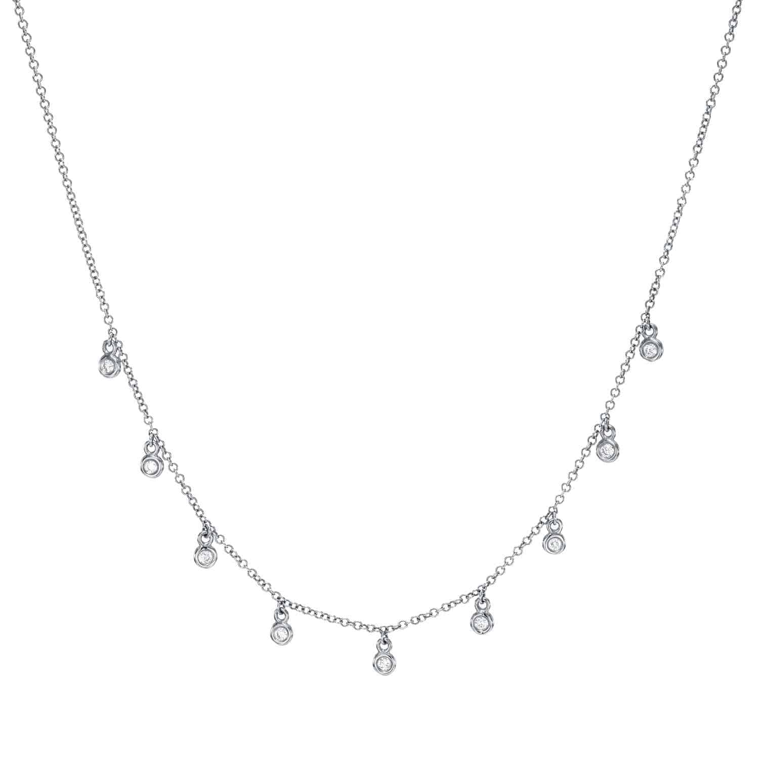 The Bezel Diamond Drop Necklace features nine small round pendants, each adorned with a sparkling clear gemstone and evenly spaced along a delicate silver chain. Exemplifying fine jewelry craftsmanship, this elegant piece stands out beautifully against a simple background.