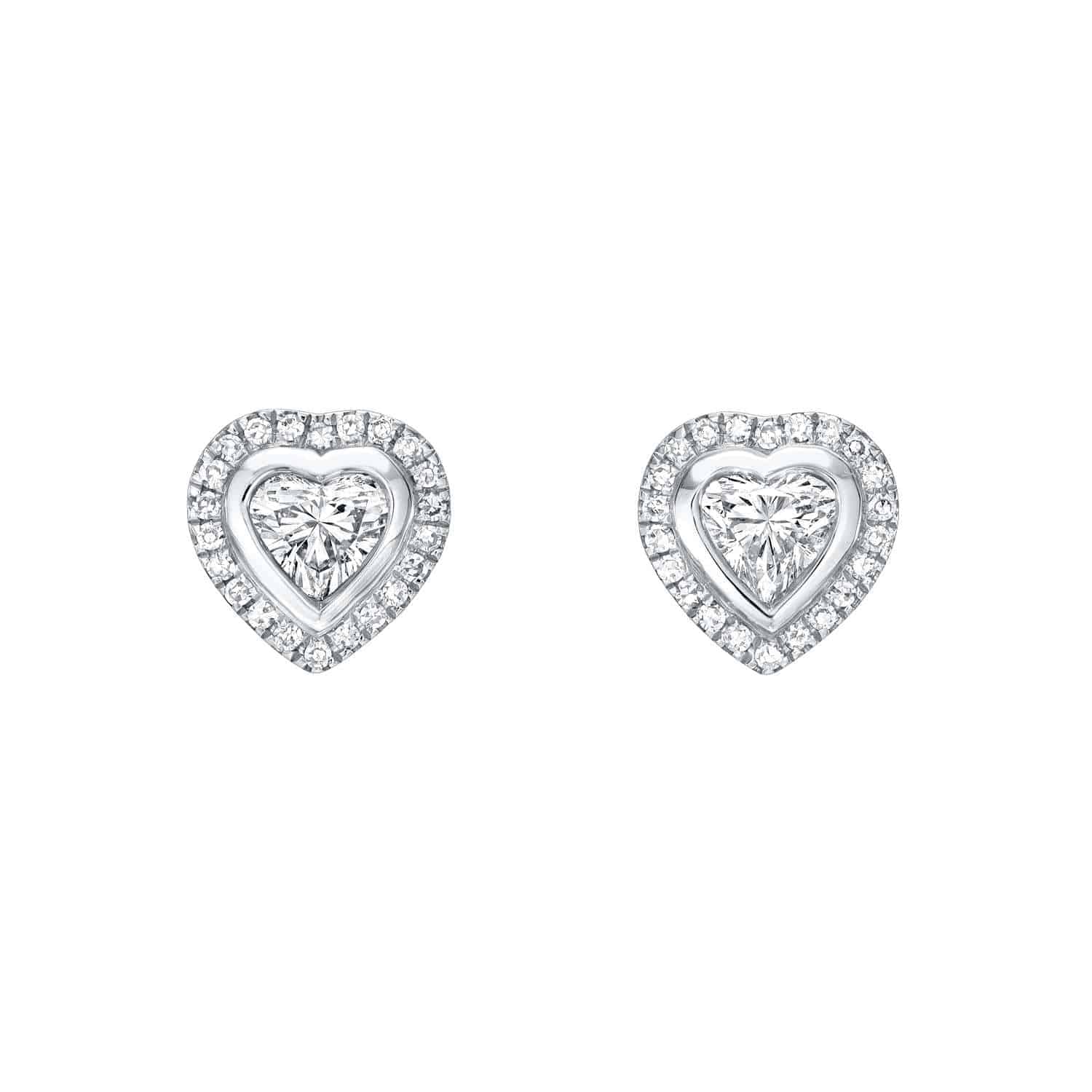 Discover the artistry of Janet Heller Fine Jewelry with the Heart-Shaped Diamond Halo Studs: each earring features a central heart-cut diamond encircled by a halo of smaller round diamonds, all set in white metal. For jewelry inquiries or to explore custom options, contact Janet Heller Fine Jewelry.