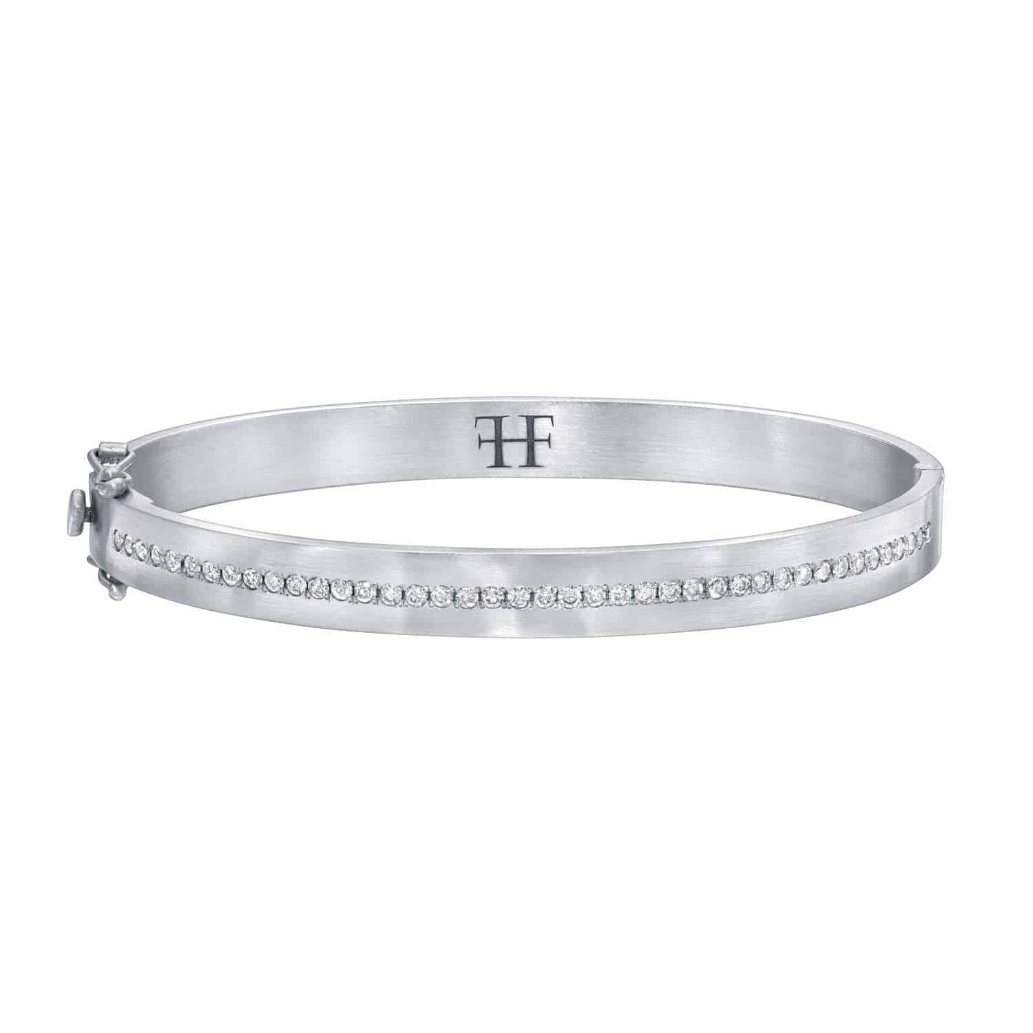 A satin diamond bangle featuring a row of small diamonds and an engraved TF logo on the inside.