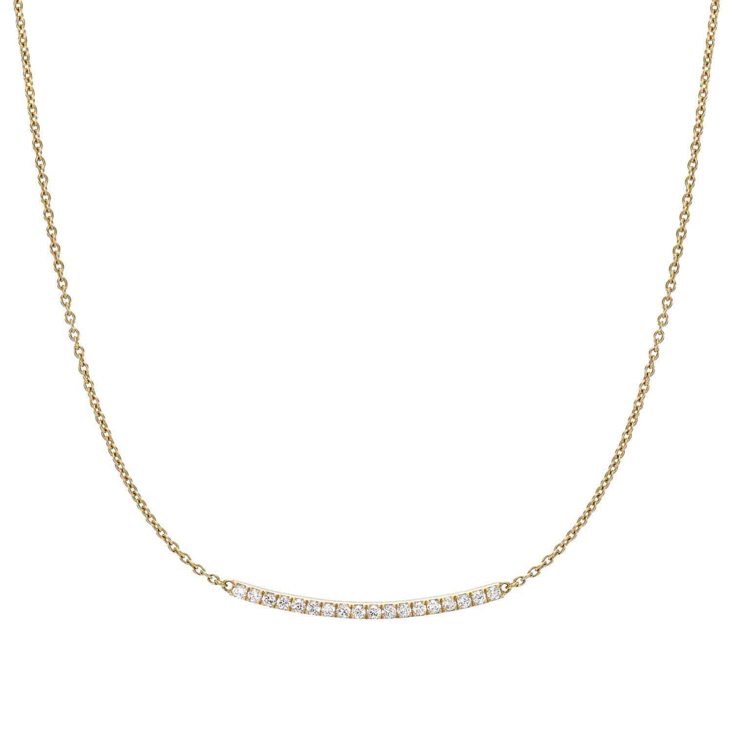 The Curved Diamond Bar Necklace is a gold chain with a horizontal bar pendant adorned with clear gemstones. This elegant piece centers the pendant on the chain. For customizations or inquiries, please contact us.