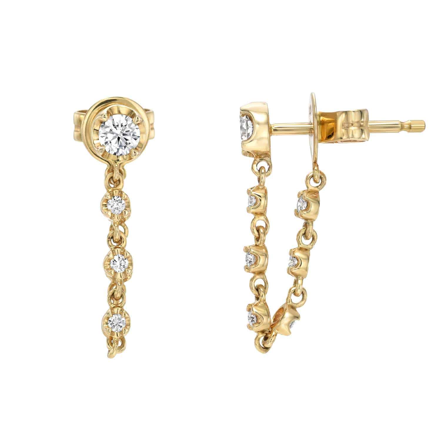 The Diamond Henley Studs from Janet Heller Fine Jewelry feature a single diamond stud connected to four vertically aligned diamonds on a dangling chain.  The Earrings can be worn alone or layered along the ear with other earrings.