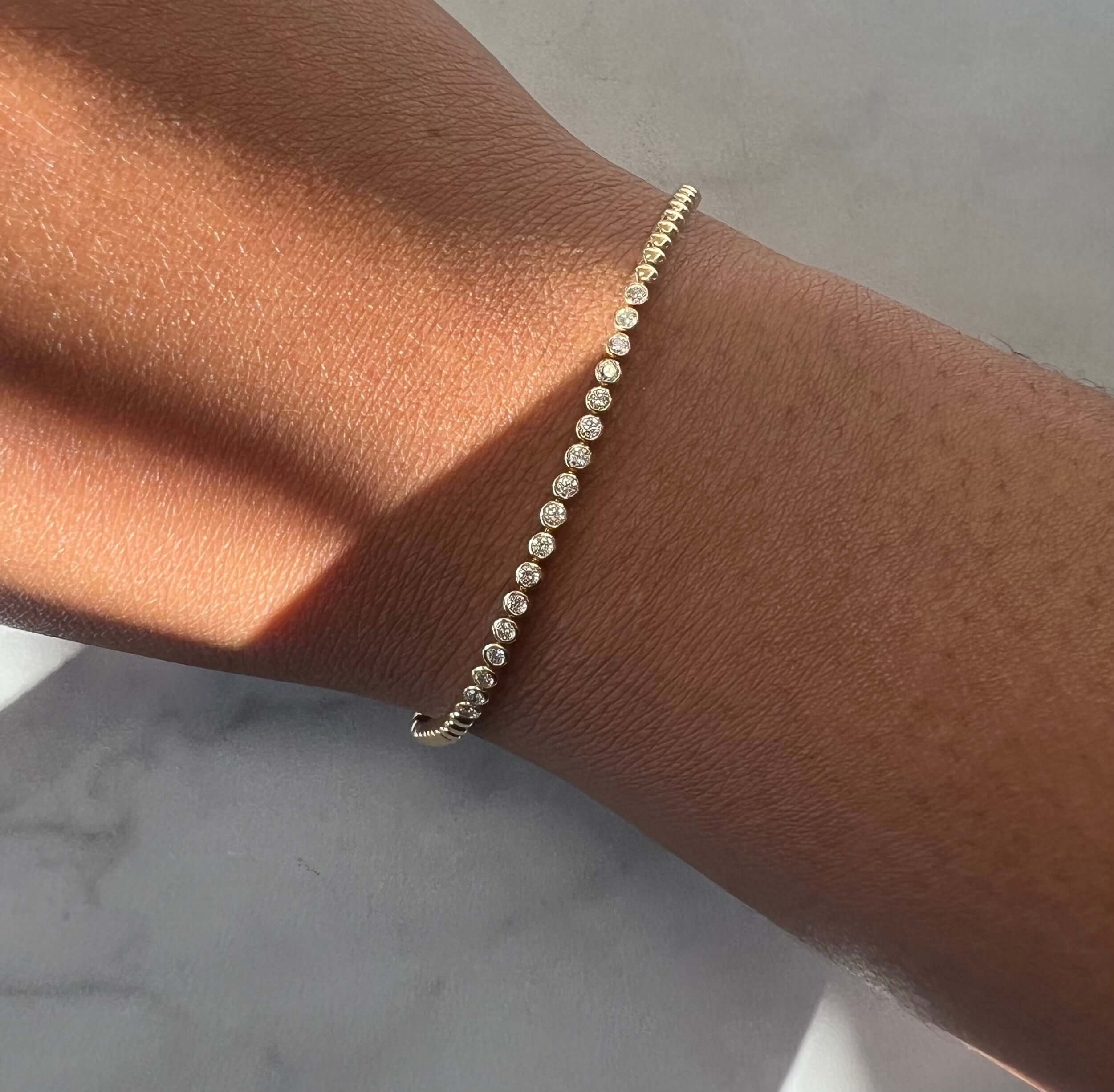 The Bezel Diamond Beaded Bracelet from Janet Heller Fine Jewelry is crafted in 14KT gold and features 17 bezel set diamonds on a beaded chain. The bracelet can be worn alone or stacked with other bracelets.