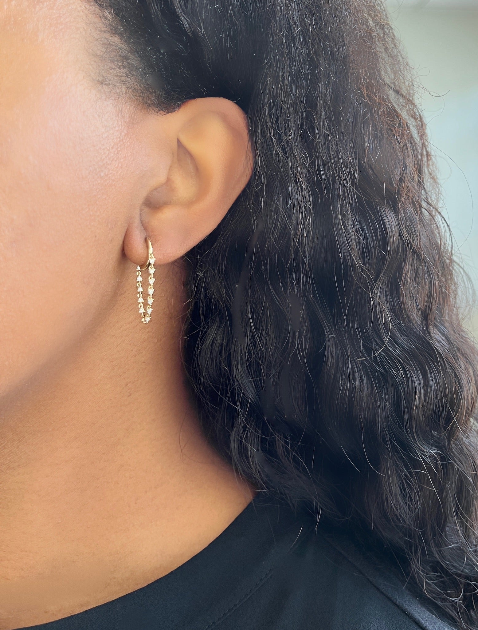 The Diamond Cascade Drop Huggies from Janet Heller Fine Jewelry are crafted in 14KT gold. The dangling hoop earrings feature evenly spaced round diamonds connected by a delicate chain. The earrings can be worn alone or layered along the ear with other earrings.