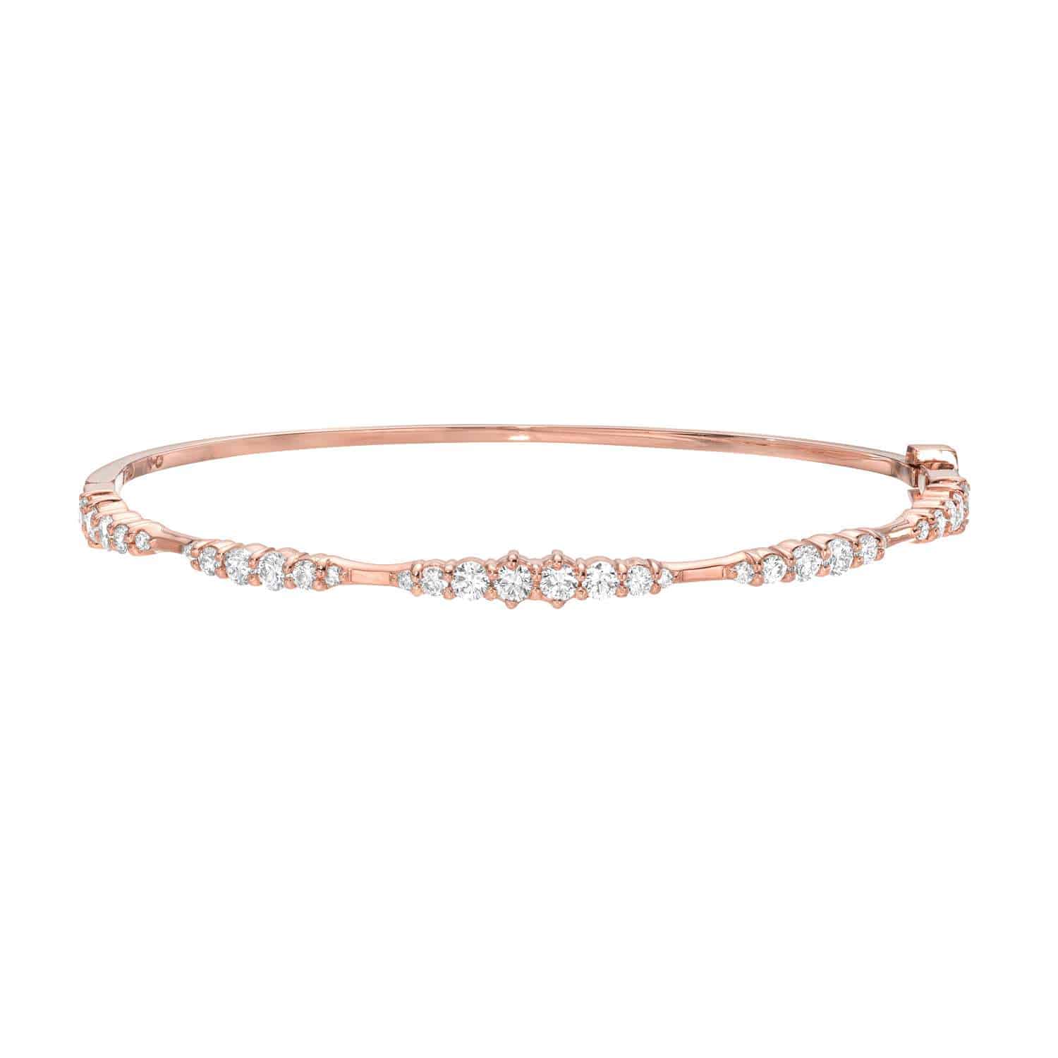 Introducing the Graduating Diamond Bangle—a slender rose gold bracelet adorned with a graduated row of sparkling white diamonds along the top and finished with a hinged clasp for easy wear. Designed by Janet Heller, this exquisite piece of fine jewelry is perfect for adding an elegant touch to any ensemble.
