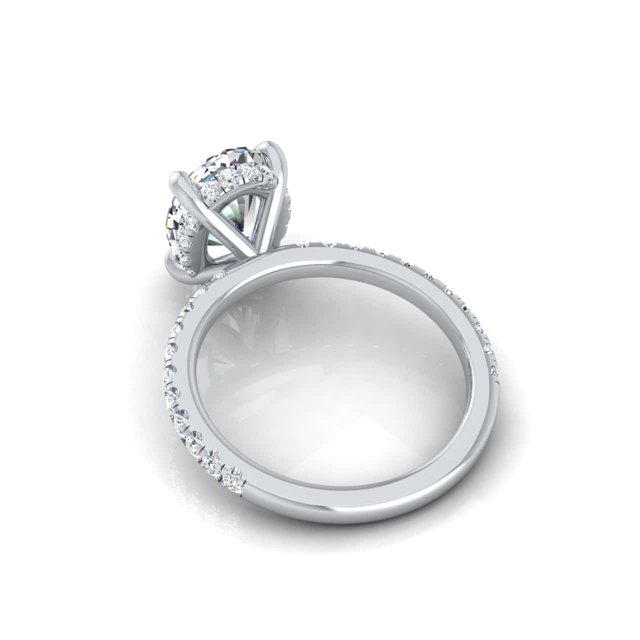 The Unity + Hidden Halo engagement ring showcases a center diamond in a four-prong setting with a pavé diamond band tapering elegantly. Displayed against a white surface, this silver ring embodies timeless sophistication.