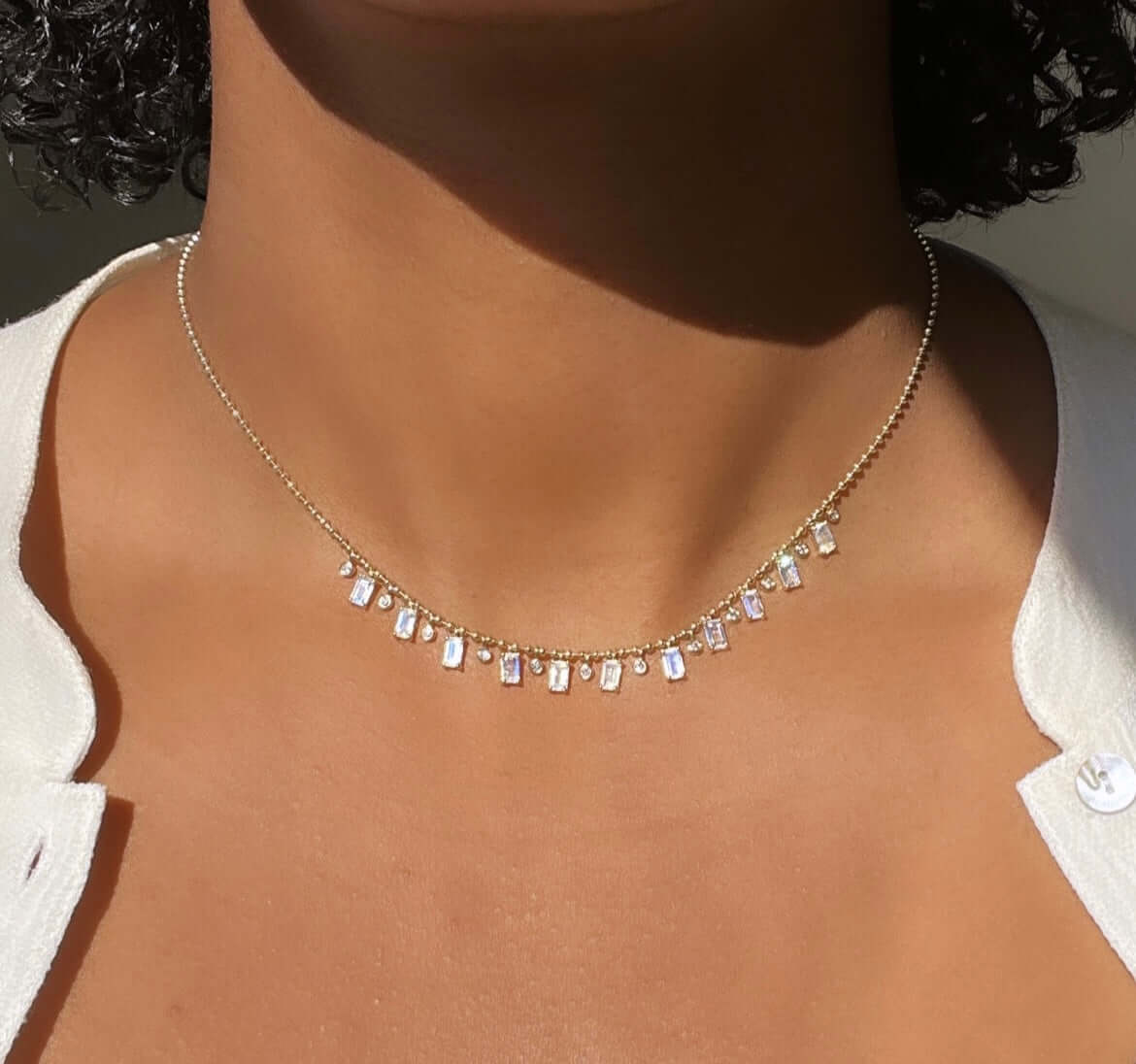The Beaded Bezel & Moonstone Diamond Necklace from Janet Heller Fine Jewelry is crafted in 14KT gold. It features emerald-cut moonstone pendants and round dangling diamonds. The necklace can be worn on its own or layered with other chains.