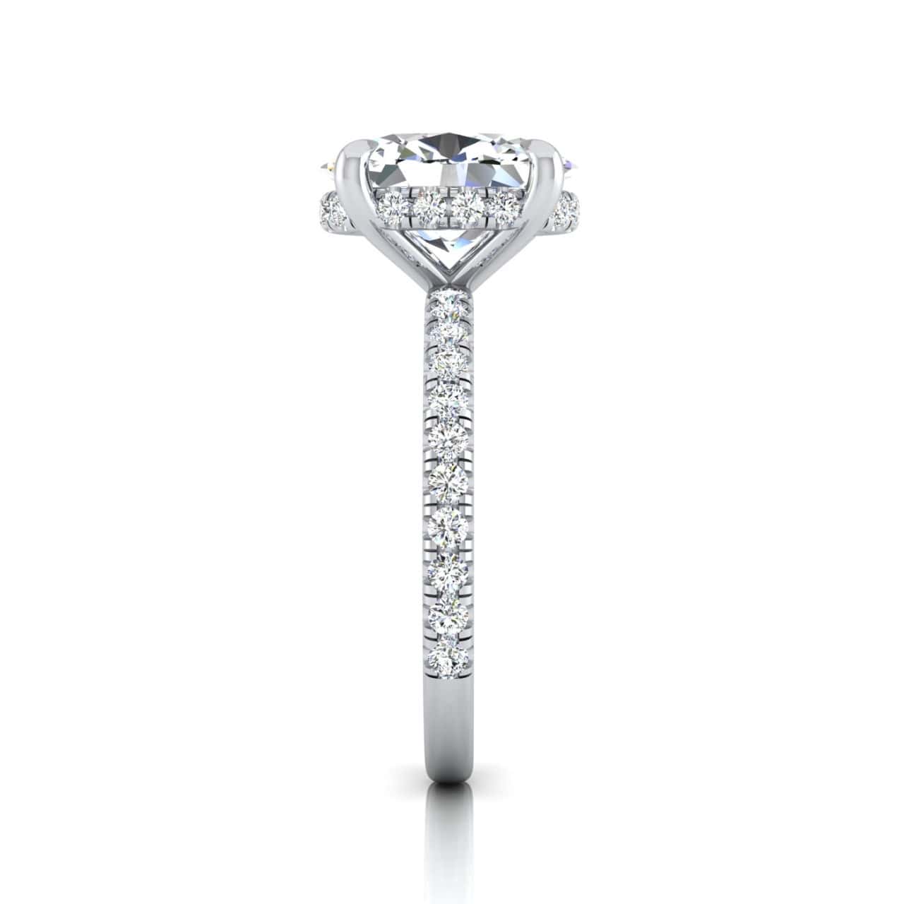 The Unity + Hidden Halo rings side view features a central diamond in a prong setting with a hidden halo, complemented by a pavé diamond band for extra sparkle. It stands elegantly upright on a reflective surface.