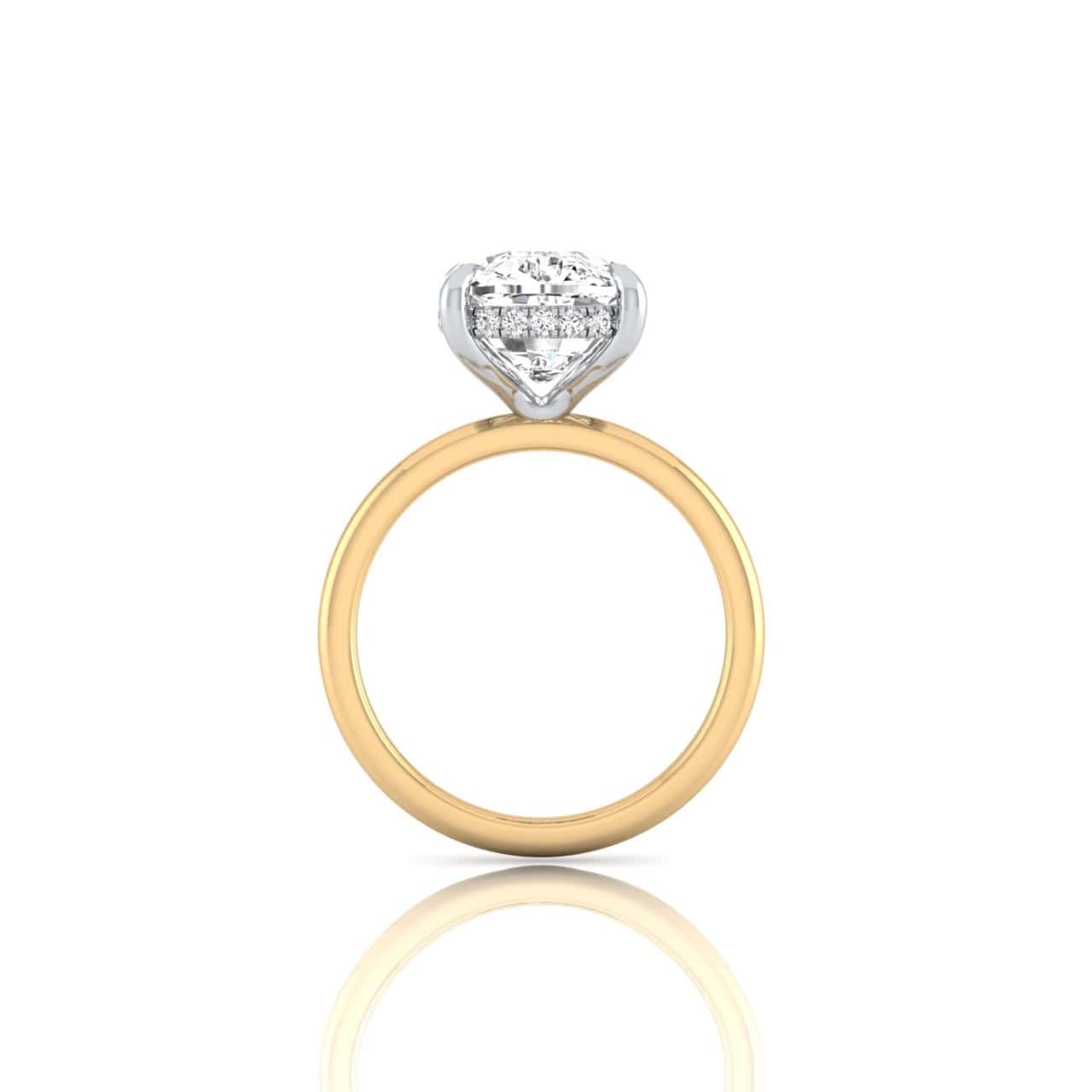 The Solitaire + Hidden Halo ring features a yellow gold band with a raised setting, showcasing a stunning cushion-cut diamond accentuated by a hidden halo of smaller stones, glistening elegantly against the white background.