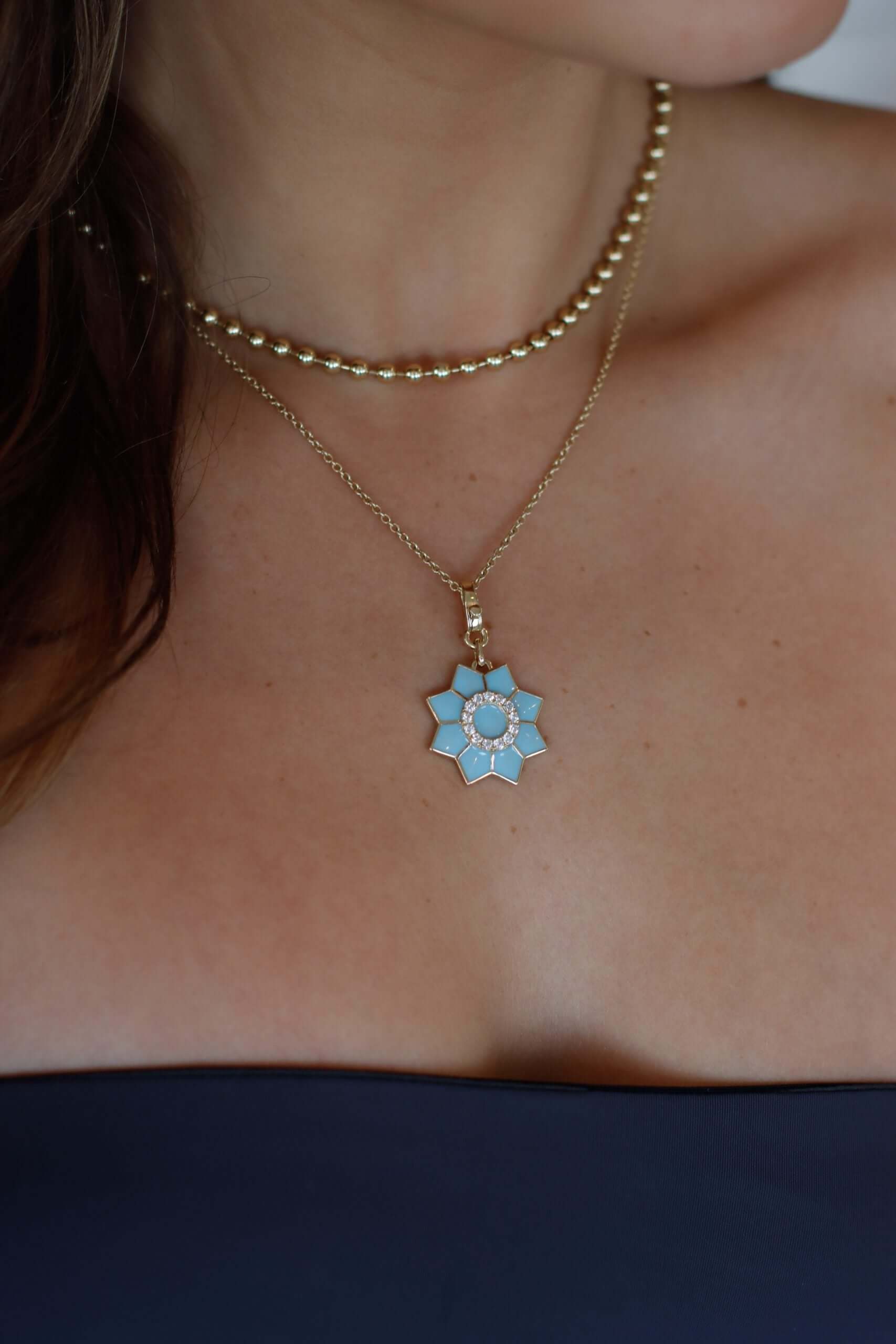 The Enamel & Diamond Flower Charm necklace by Janet Heller Fine Jewelry, features a blue flower pendant with a circular center surrounded by diamonds. The clasp which adorns a single diamond clips easily onto various Janet Heller Fine Jewelry necklaces and chains.