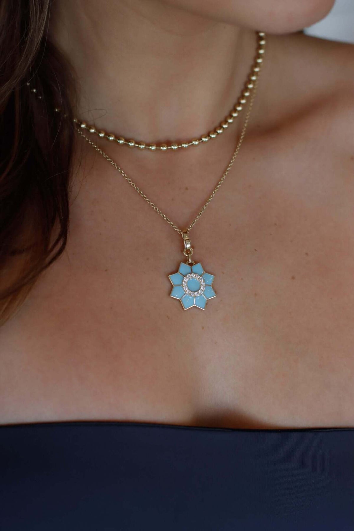 The Enamel & Diamond Flower Charm necklace by Janet Heller Fine Jewelry, features a blue flower pendant with a circular center surrounded by diamonds. The clasp which adorns a single diamond clips easily onto various Janet Heller Fine Jewelry necklaces and chains.