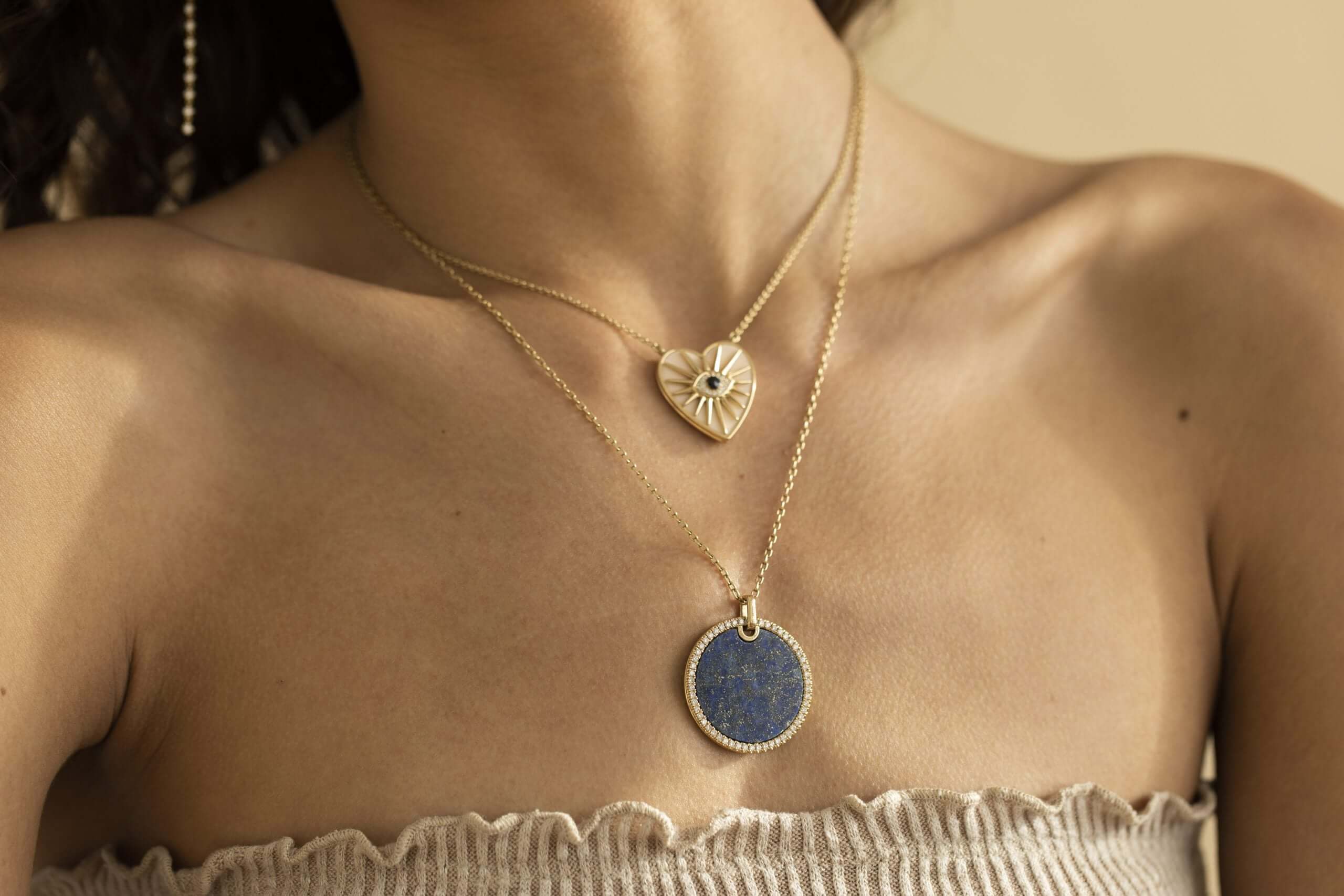 The Large Lapis Pendant Necklace from Janet Heller Fine Jewelry is crafted in 14KT gold. The round lapis charm is edged in diamonds. The necklace can be worn alone or layered with other chains.