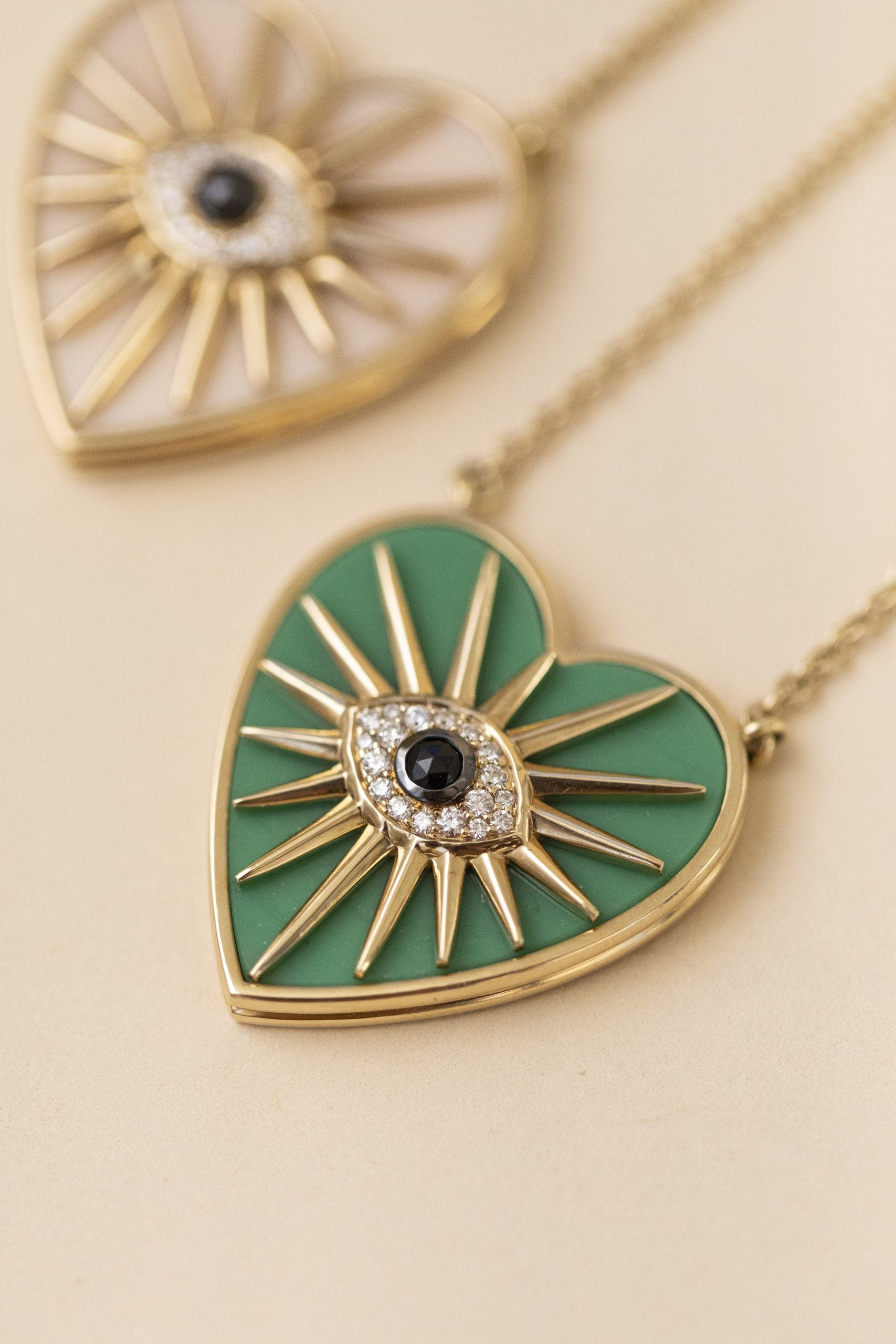 Enhance your look with the Green Chrysoprase Heart Burst Necklace from janethellerfinejewelry—heart-shaped sunburst design, eye motif center, green with black and white detailing edged in gold. Unique customizations available for personal flair.