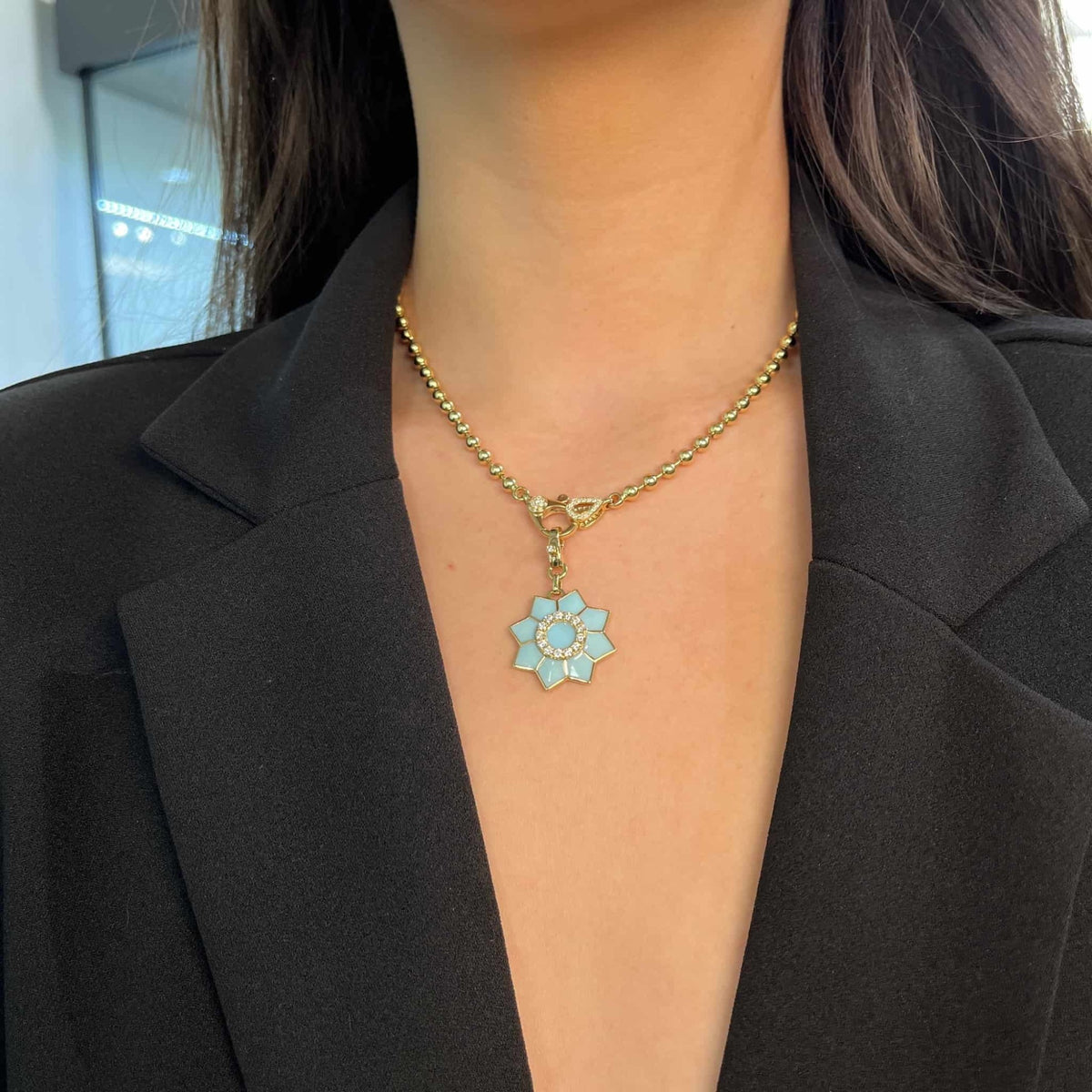 The Enamel & Diamond Flower Charm necklace by Janet Heller Fine Jewelry, features a blue flower pendant with a circular center surrounded by diamonds. The clasp which adorns a single diamond clips easily onto various Janet Heller Fine Jewelry necklaces and chains.