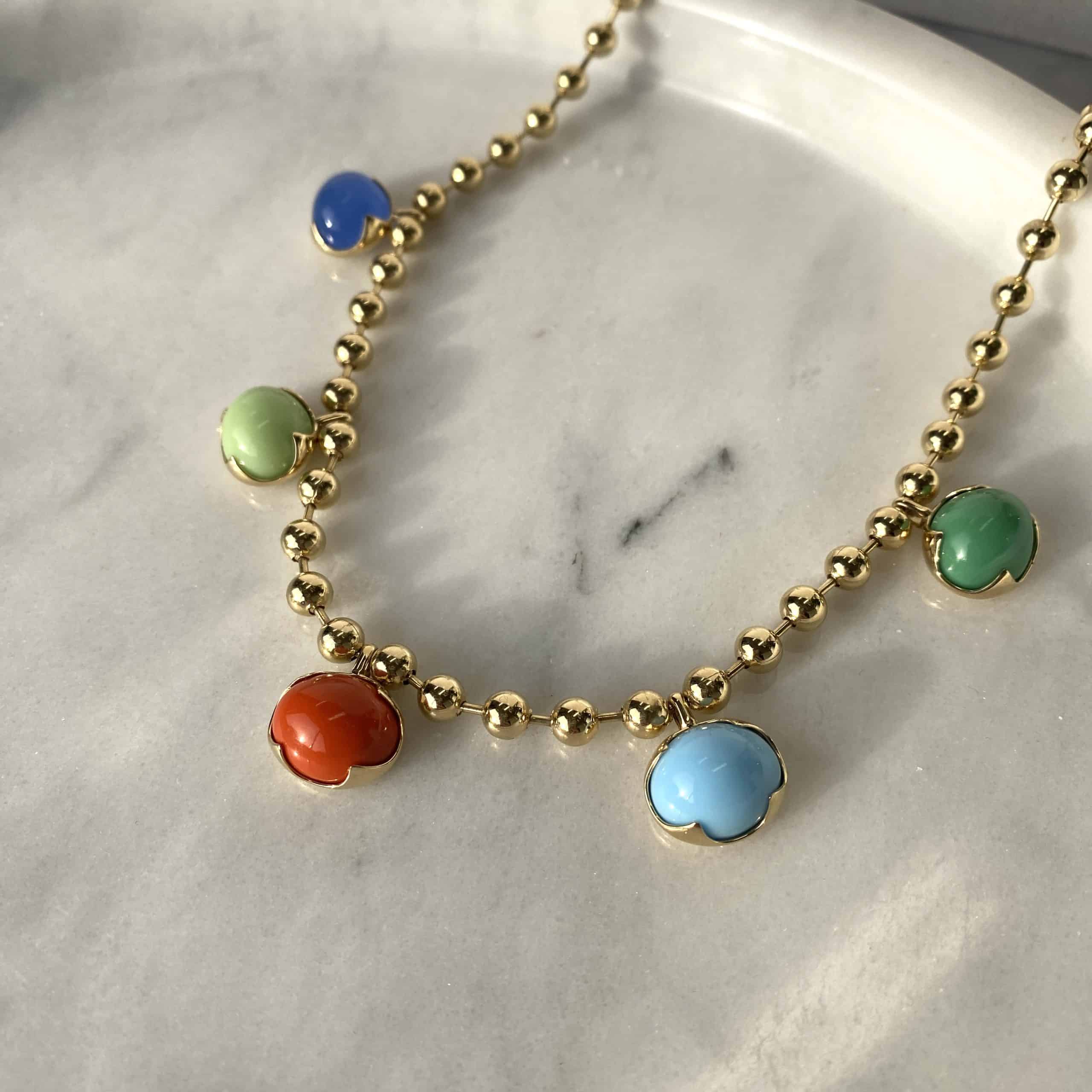 The Mixed Colored Stone Necklace from Janet Heller Fine Jewelry is crafted in 14KT gold. The necklaces features gold beads and colorful round pendants in blue, orange, green, light green and light blue.