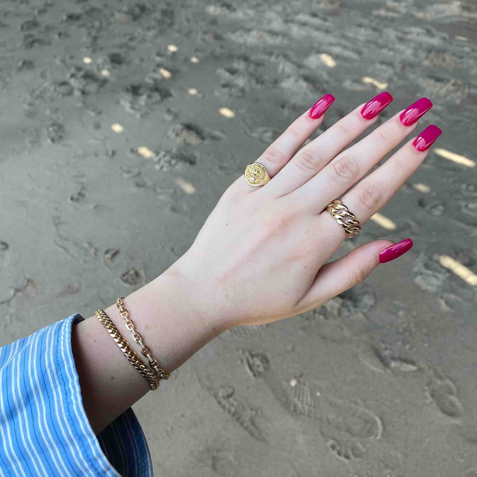 The Diamond Lion Ring from Janet Heller Fine Jewelry is crafted in 14KT gold. The band showcases a rounded top with a small diamond framed by the face and mane of a lion.