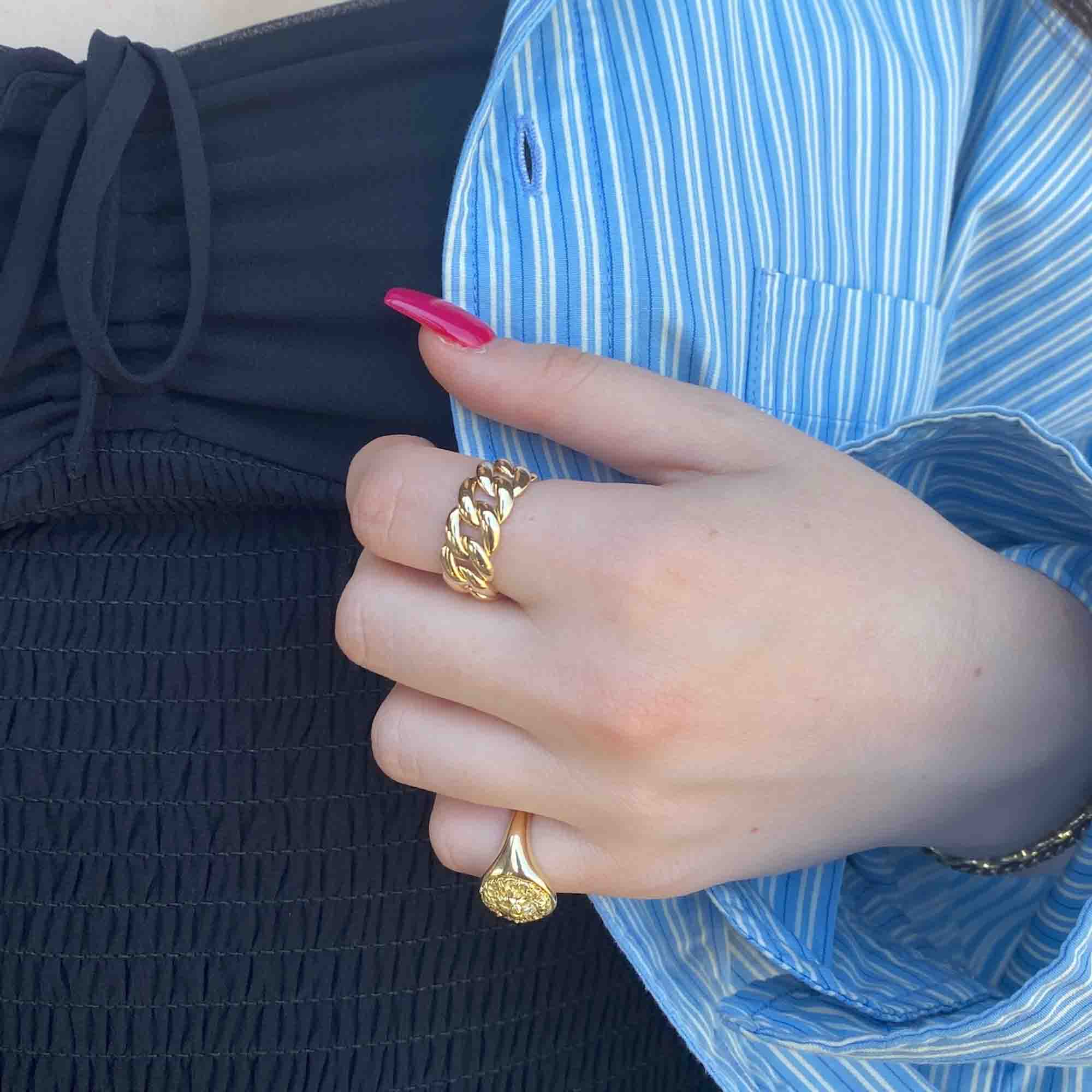 The Plain Cuban Link Ring from Janet Heller Fine Jewelry is is crafted in 14KT gold. It features an interlocking chain design with rounded links.