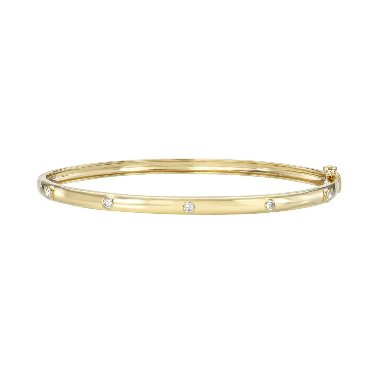 The Diamond Studded Bangle from Janet Heller Fine Jewelry is crafted in 14KT gold. The bracelet is adorned with 5 small, evenly spaced round diamonds and includes a hinged closure. The bangle can be worn alone or stacked with other bracelets.