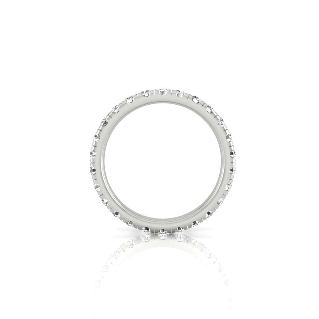 The 1ct Round Diamond Eternity Ring in 18KT white gold features small, dazzling VS clarity diamonds encrusted around its entire band, elegantly displayed on a reflective white background.