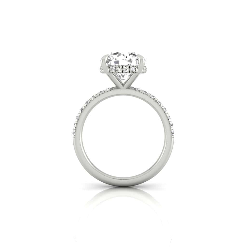 The silver engagement ring showcases a large round diamond solitaire in a raised prong setting, complemented by a French Pavé band with small diamonds. The Amélie + Hidden Halo design enhances its sparkle against a white background.