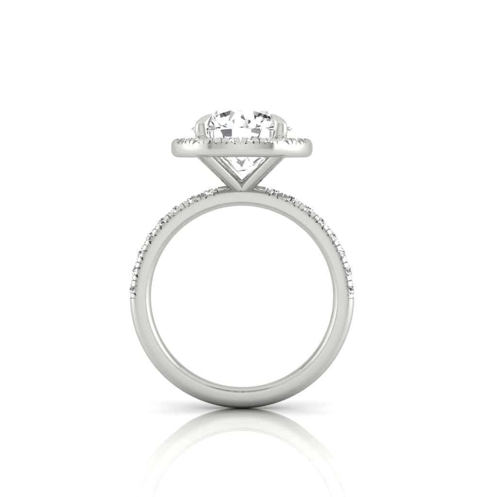 A side view of the Amélie + Full Halo ring reveals a large, round center diamond encircled by a diamond halo in a prong setting. The French Pavé band is embellished with small diamonds for added sparkle, elegantly displayed against a plain white background.