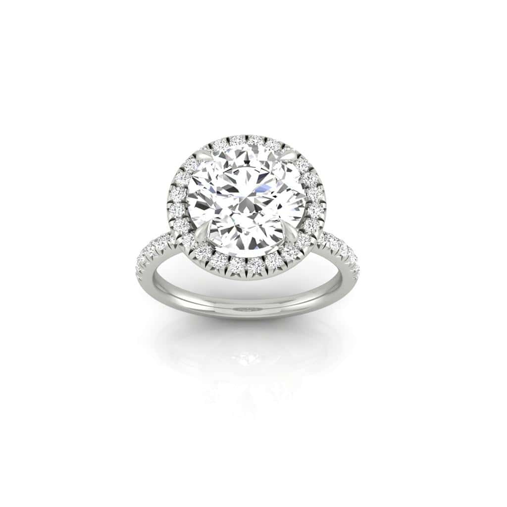 The Amélie + Full Halo Ring from Janet Heller Fine Jewelry features a single prong-set center diamond with a full halo of diamonds, set on a French Pavé band adorned with small diamonds.