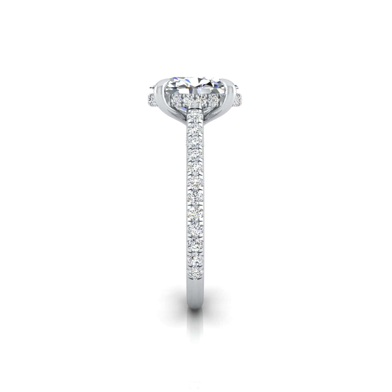 The Unity + Hidden Halo features a side view of a silver engagement ring with a round-cut diamond center stone in a hidden halo setting. The band is embellished with small diamonds, offering elegance through its minimalist yet sparkling design.