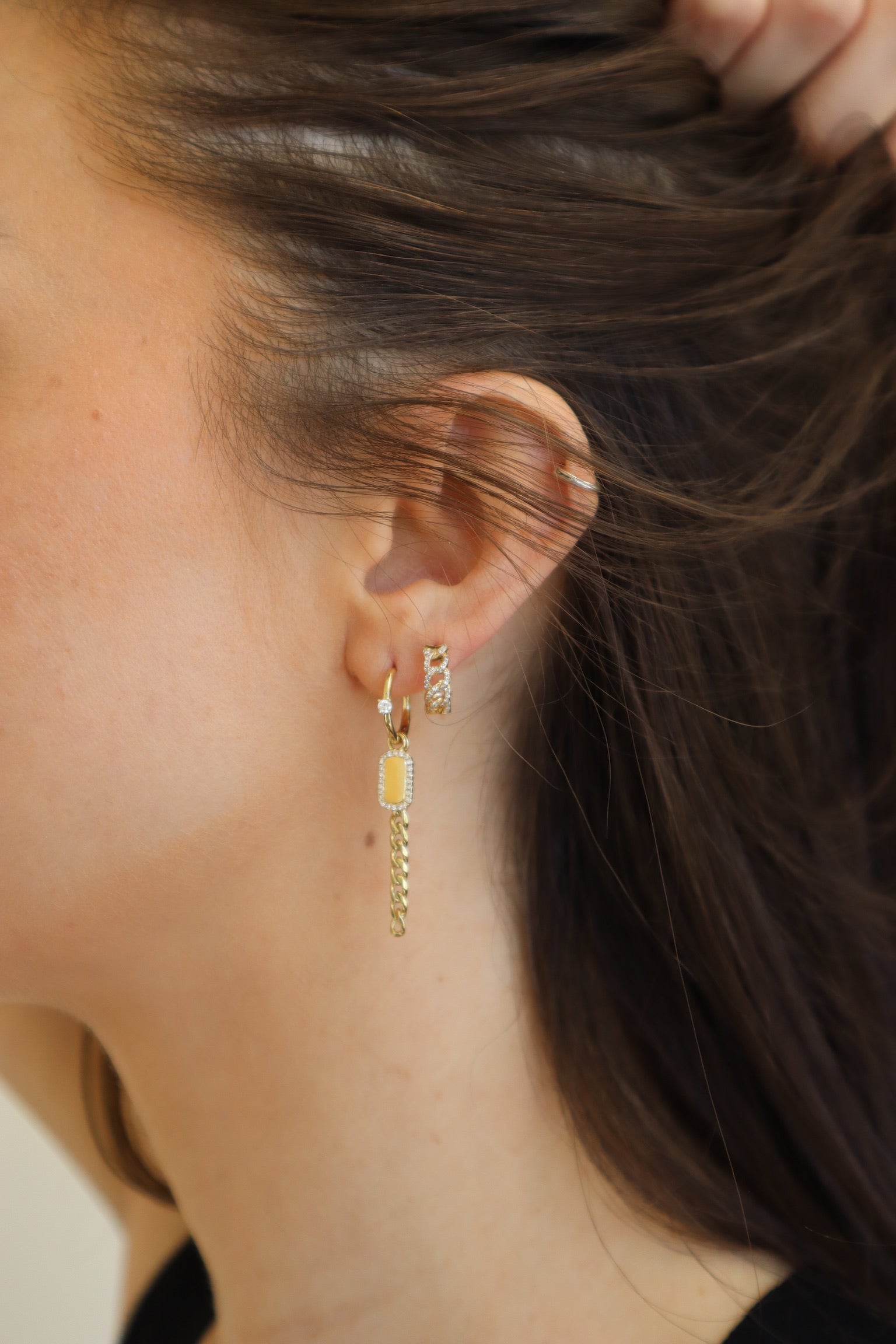 The Diamond Curb Link Dog Tag Drop Huggies from Janet Heller Fine Jewelry are crafted in 14KT gold.  The hoop earrings feature a chain link drop with a dog tag charm framed in small diamonds.  The dangling earrings can be worn alone or layered along the ear with other earrings.  