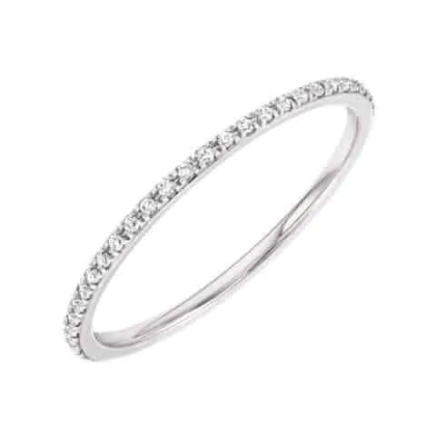 Introducing the Micro Pavé Eternity Ring by Janet Heller—a slender white gold band featuring a continuous row of small round diamonds, available for preorder and elegantly displayed on a white background.