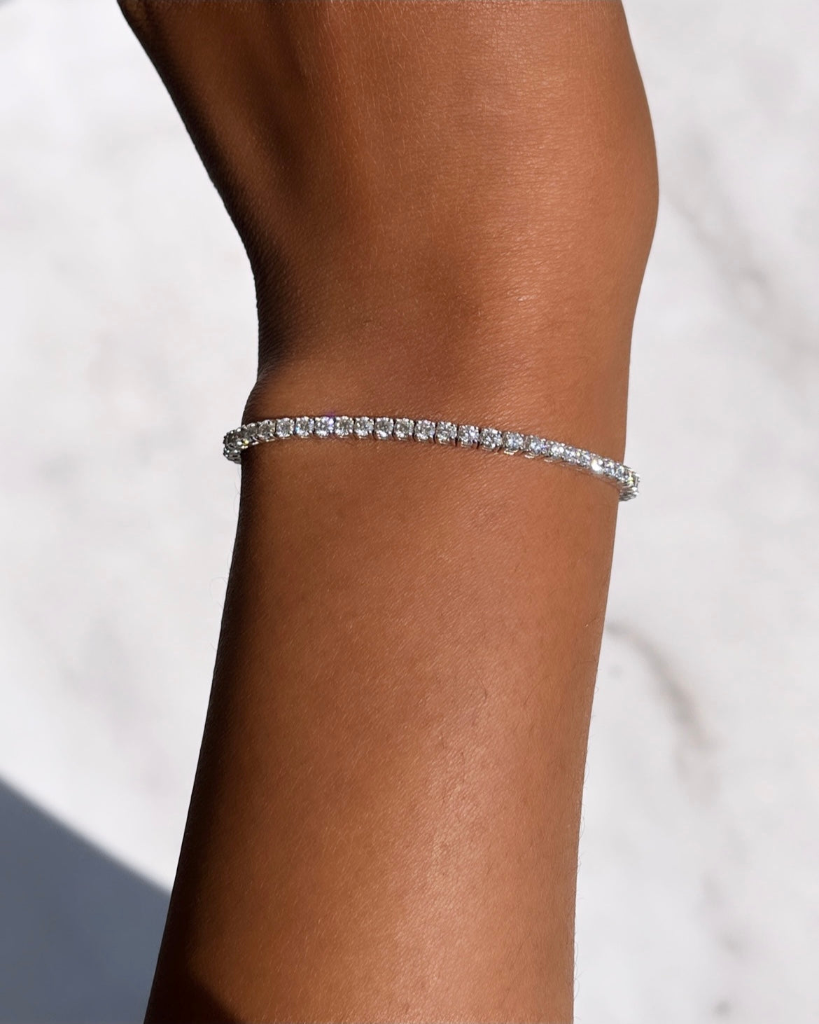 Close-up of a wrist adorned with the 3ct Round Diamond Tennis Bracelet, showcasing small sparkling stones in a continuous line against smooth skin.